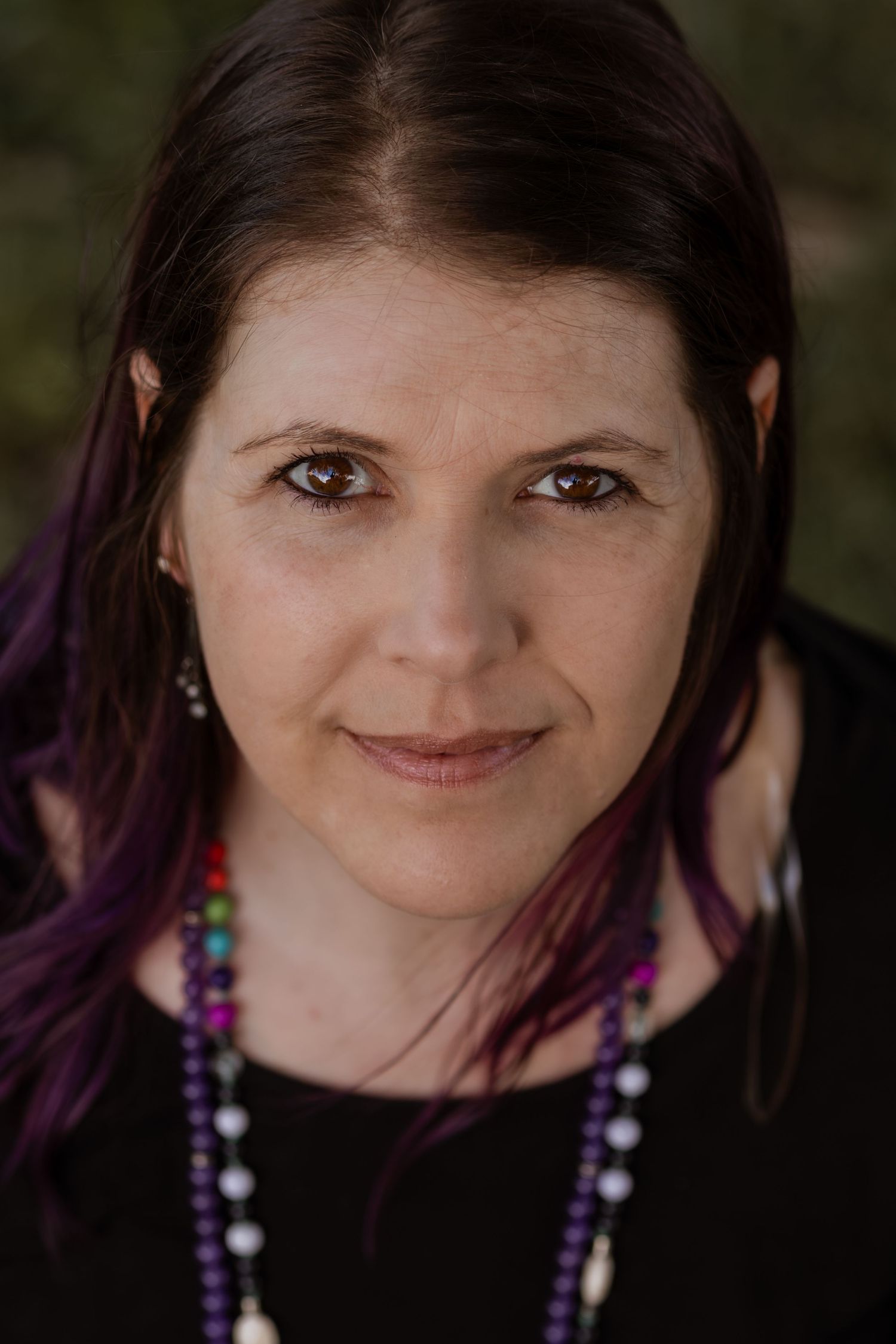 Close-up portrait series showing purple hair and colorful beaded necklace against dark background.