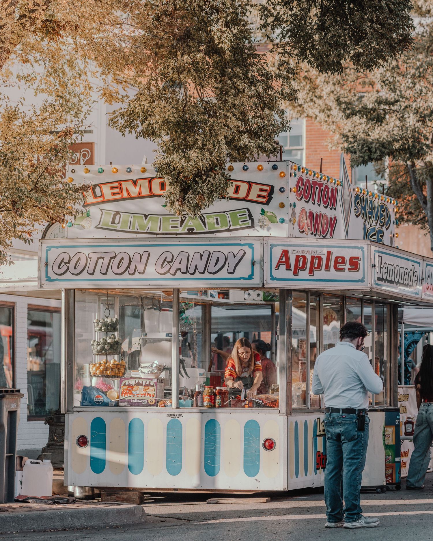 Vintage-style carnival food stalls selling cotton candy, apples, and other treats under autumn trees.