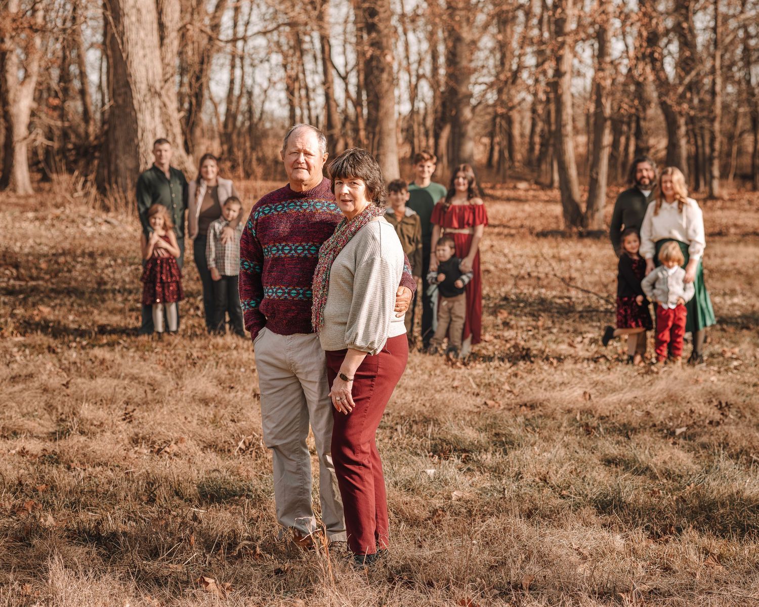Family members spread out across a wooded hillside during an autumn photoshoot.