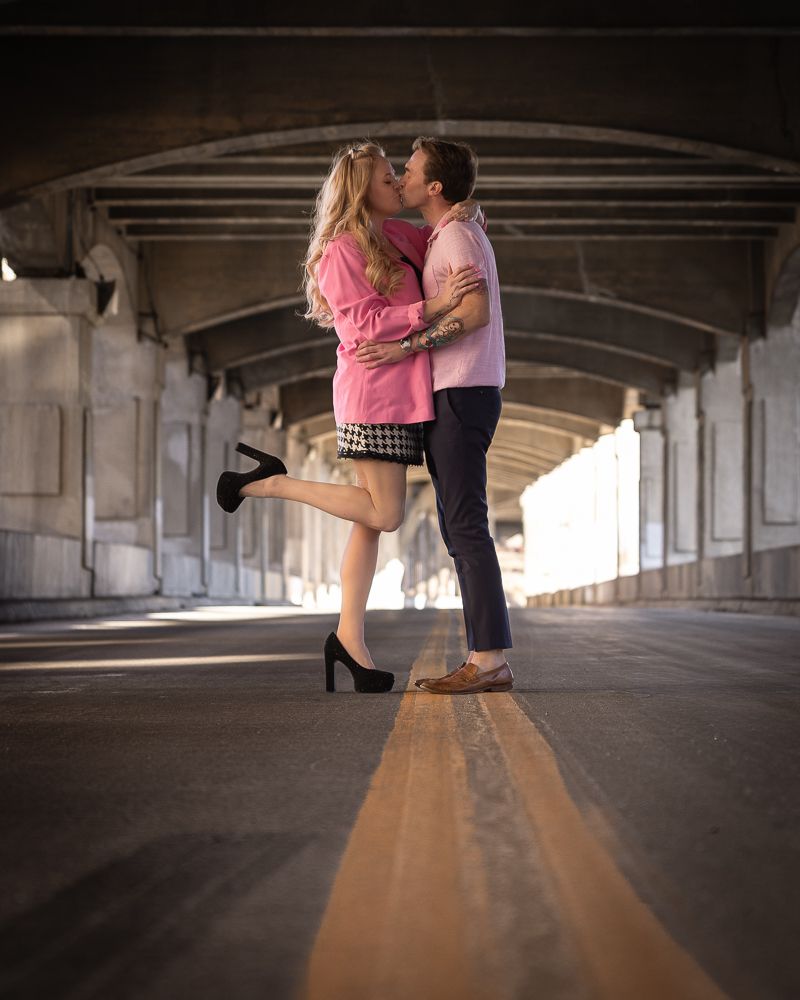 Couple dancing together in a dimly lit concrete parking structure with dramatic lighting and shadows.