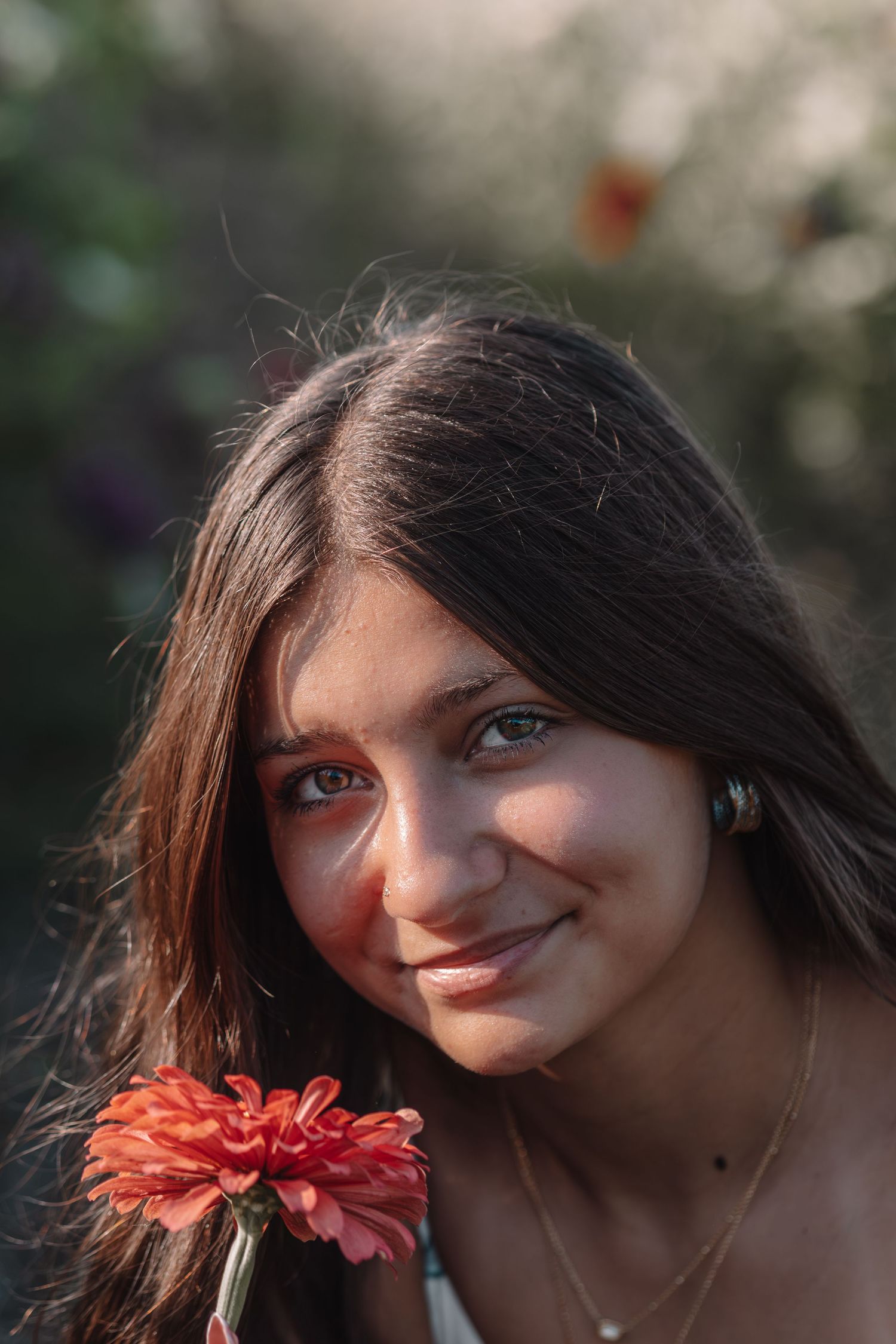 Artistic close-up portrait with a coral zinnia flower in warm sunset light.