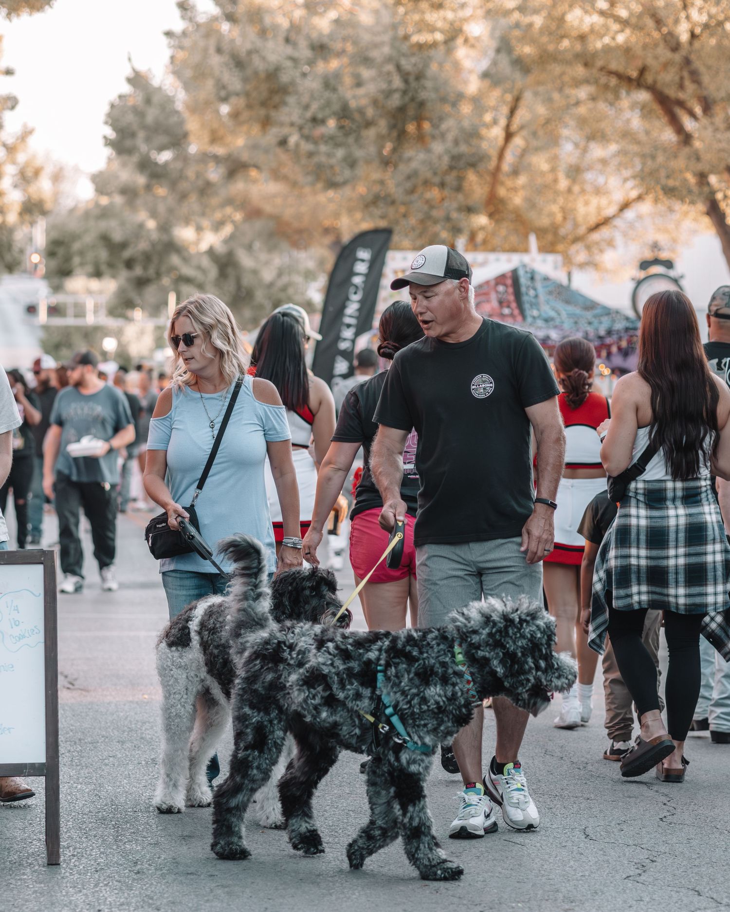 Crowd of festival attendees walking along a path with autumn trees in the background.