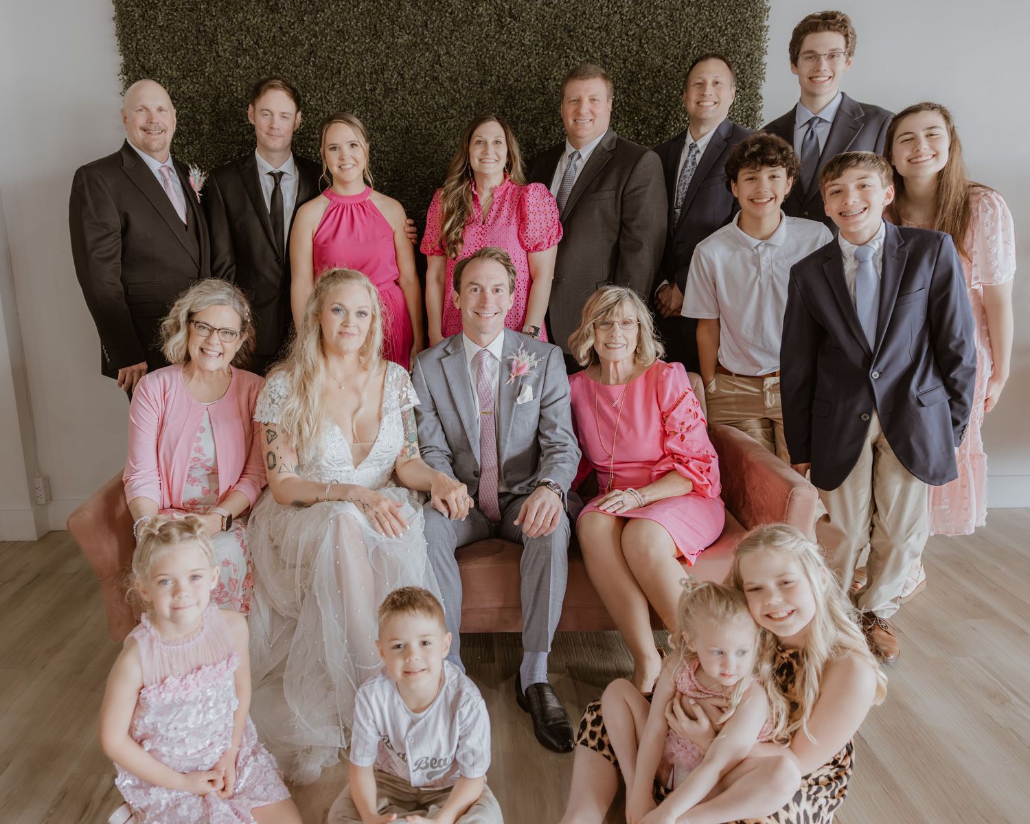 Large family group portrait at a wedding celebration, featuring bride and groom surrounded by relatives in formal attire.