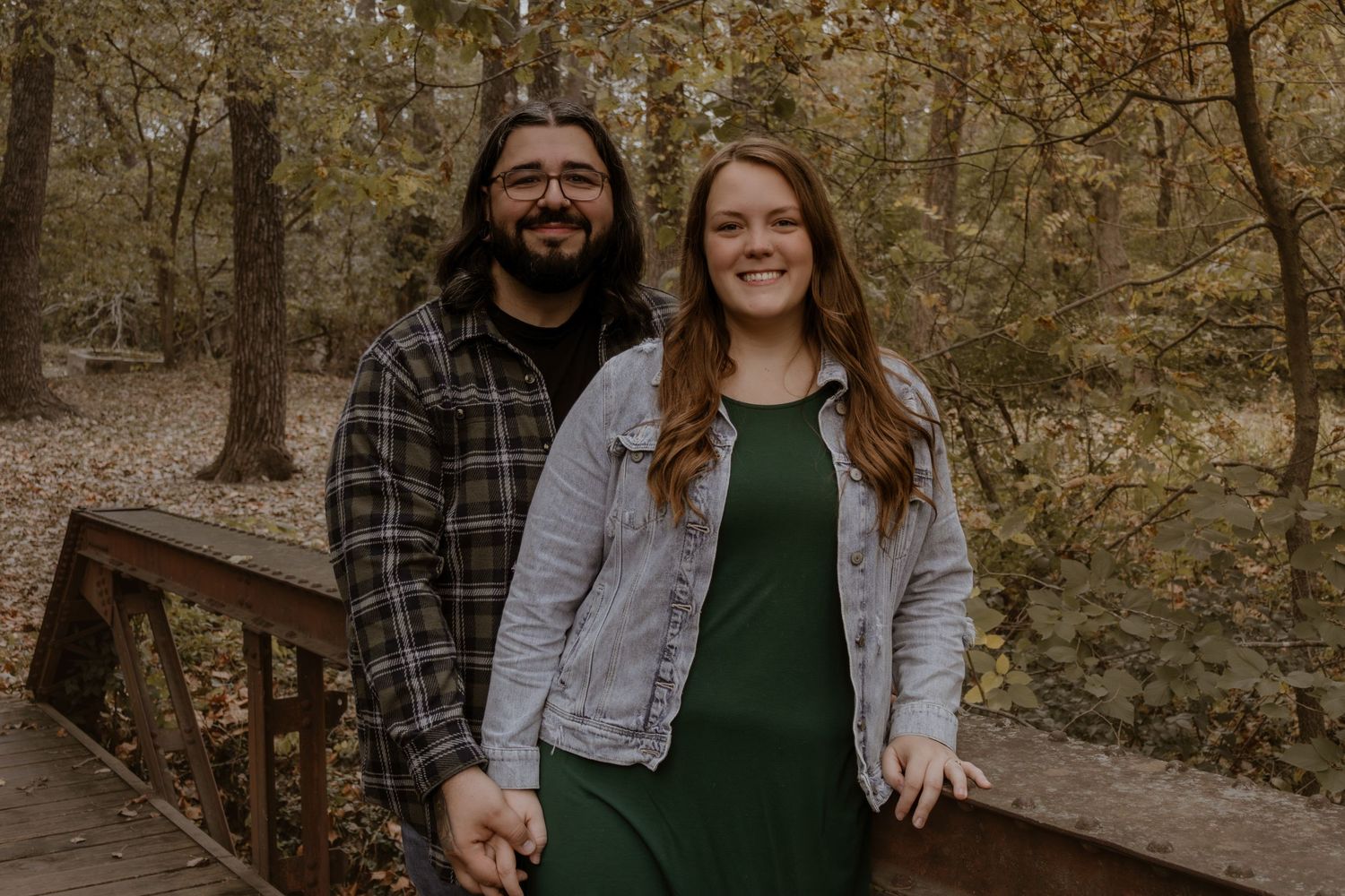 Casual outdoor family portrait session on a wooden walkway in autumn woods.