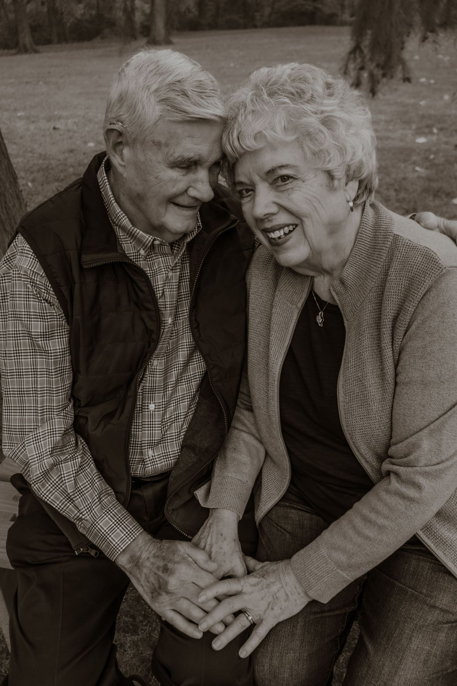 Black and white photo series showing an elderly couple laughing and embracing on a bench outdoors.