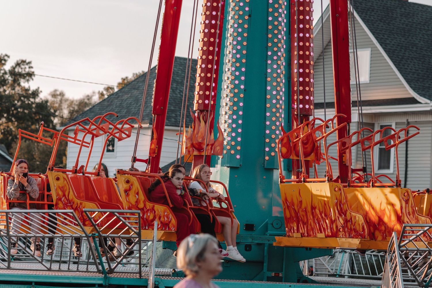 Carnival rides with red and teal colors illuminated against an evening sky.