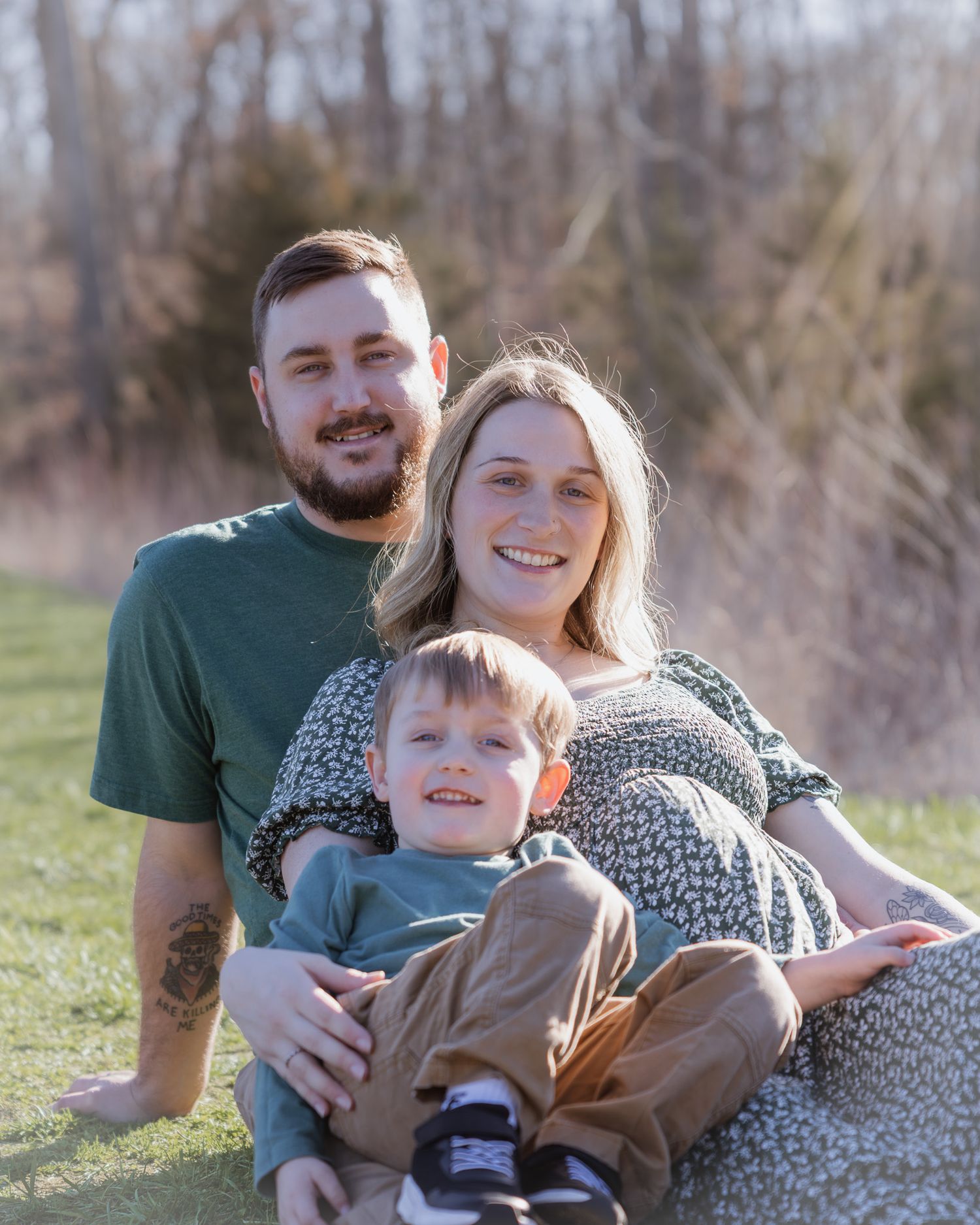 Candid family photo on grassy hill showing joyful expressions and casual outdoor style.