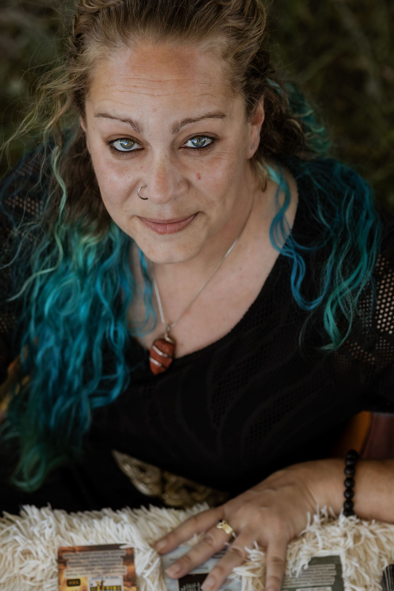 A series of moody portraits showing someone with vibrant teal hair in a dark setting.