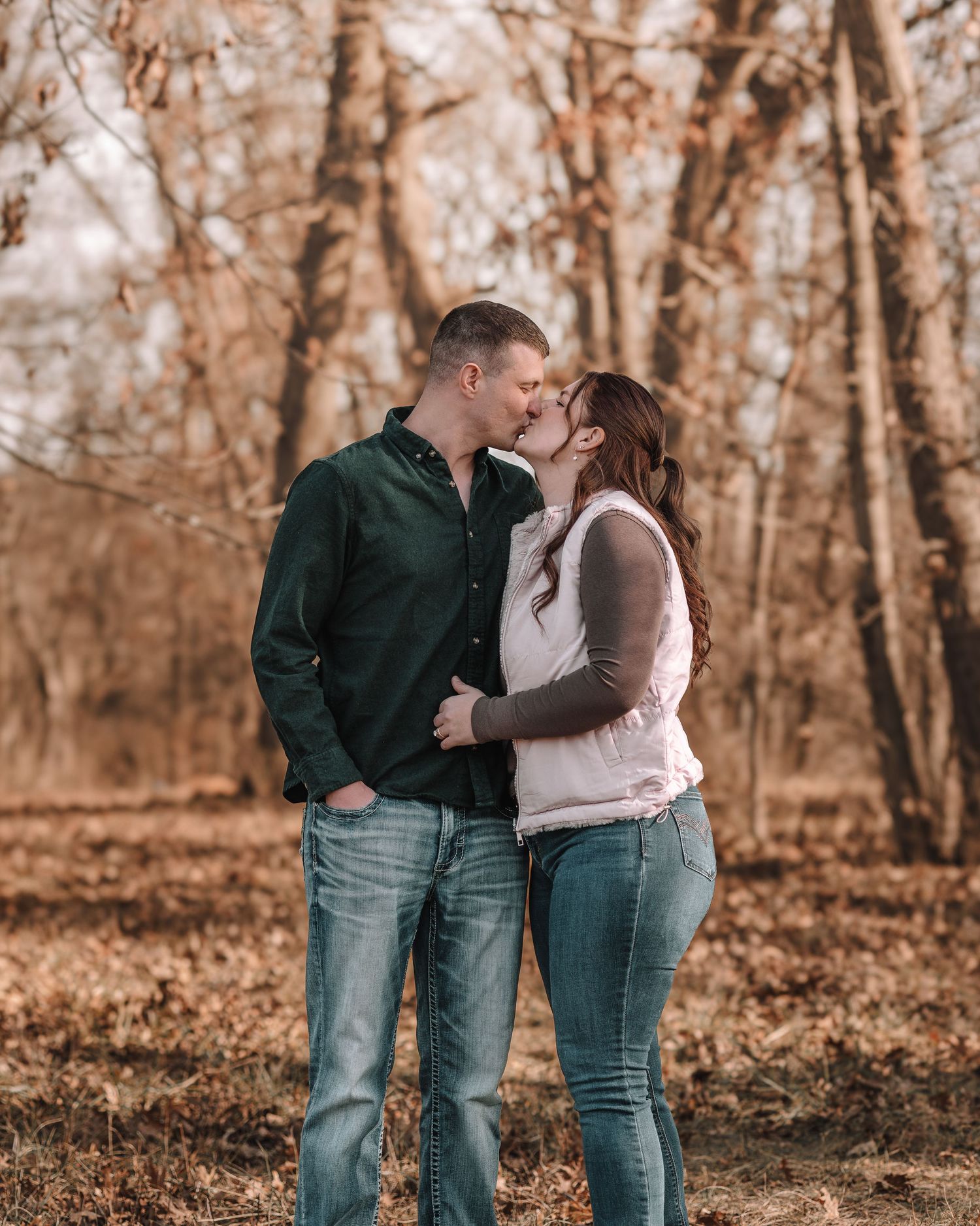 Romantic couple sharing an intimate moment while standing together in a wooded autumn setting.