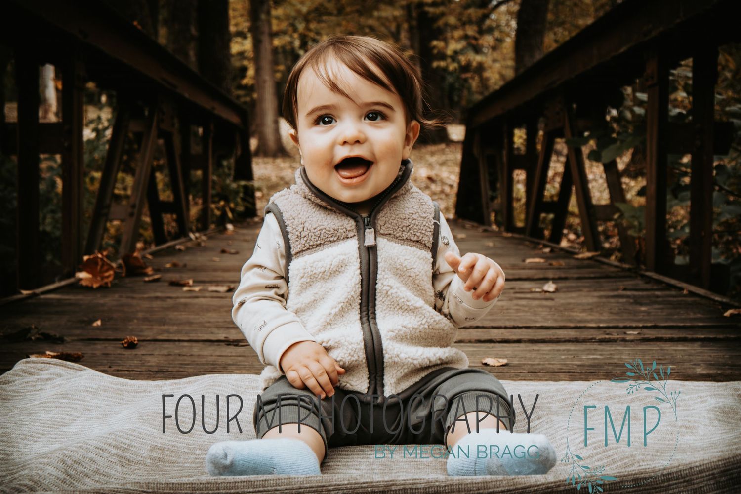 A small child in a beige jacket explores a wooden bridge in an autumn forest setting.