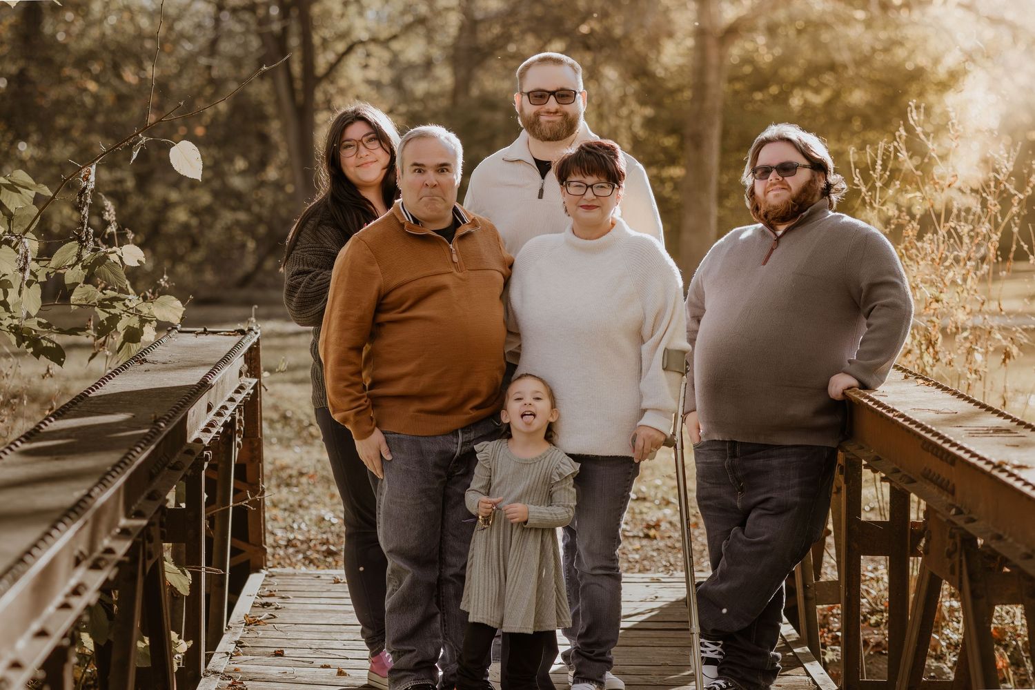 Family enjoying a warm autumn day together outdoors in a park with golden sunlight filtering through trees.