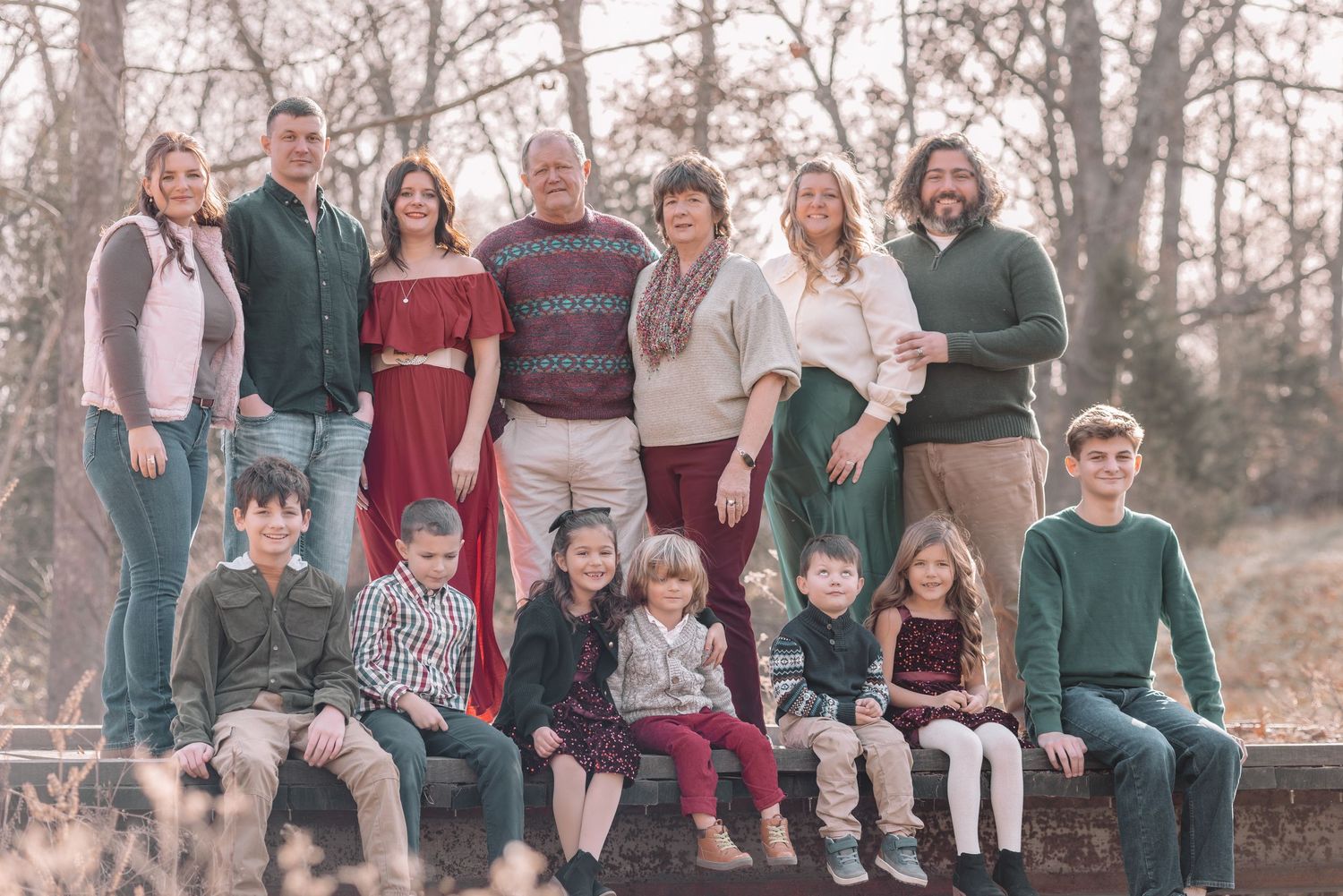 A large group gathers outdoors for a casual photo session in an autumn setting with trees in the background.