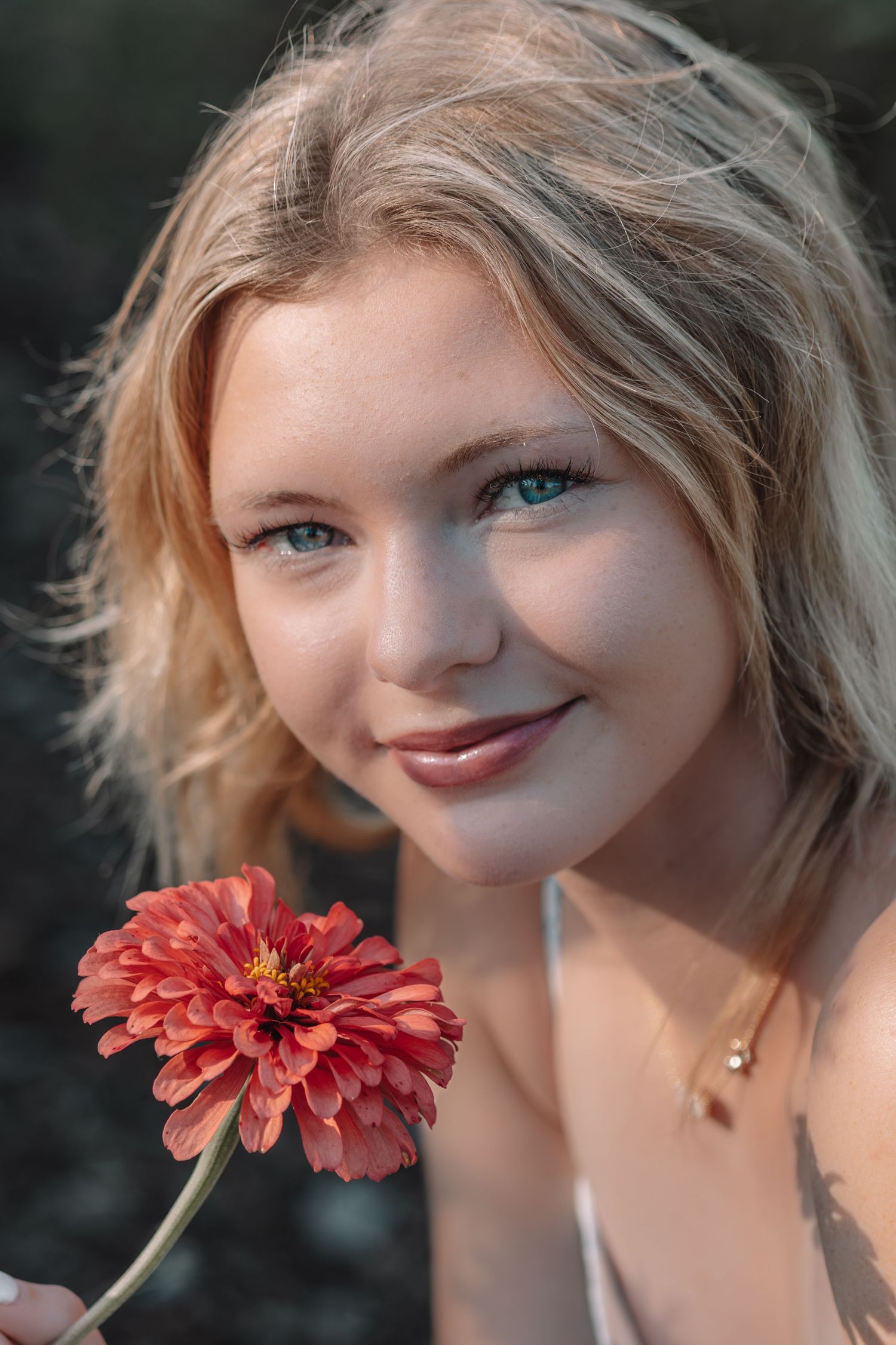 Whimsical close-up portrait featuring a coral zinnia flower in natural light.