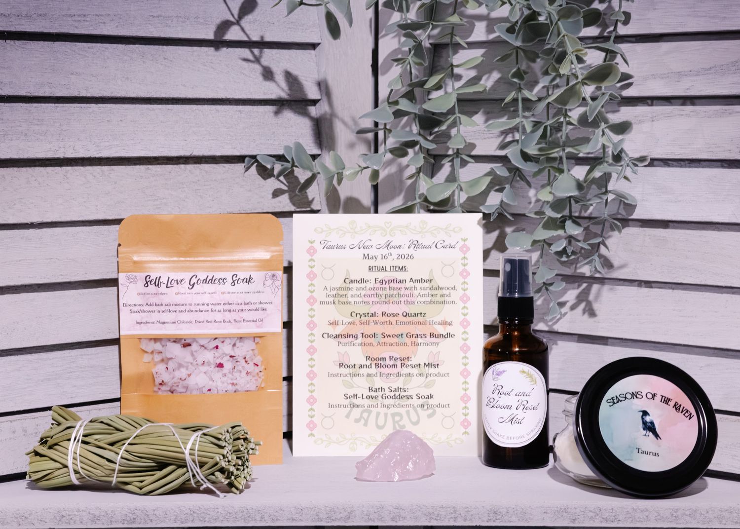 Artisan self-care gift set with bath salts, sage bundle, amber spray bottle, face cream, and crystal on white wood.