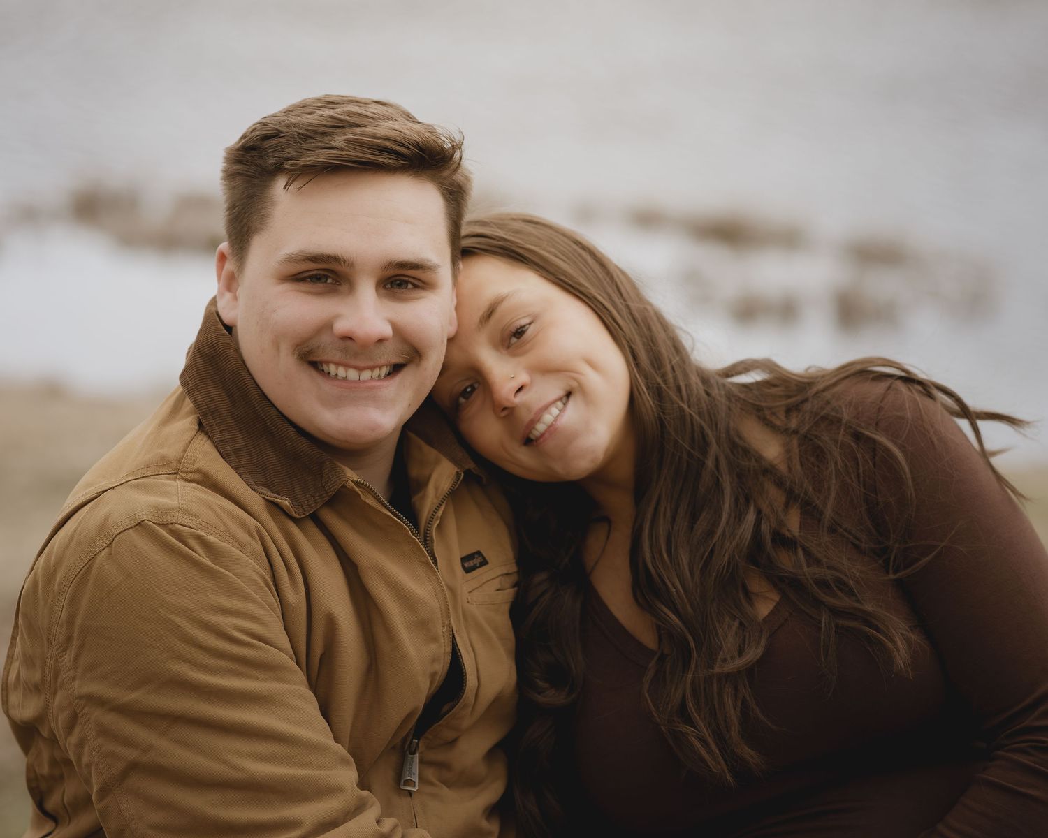 A cozy couple in matching tan and brown outfits share an intimate moment outdoors.