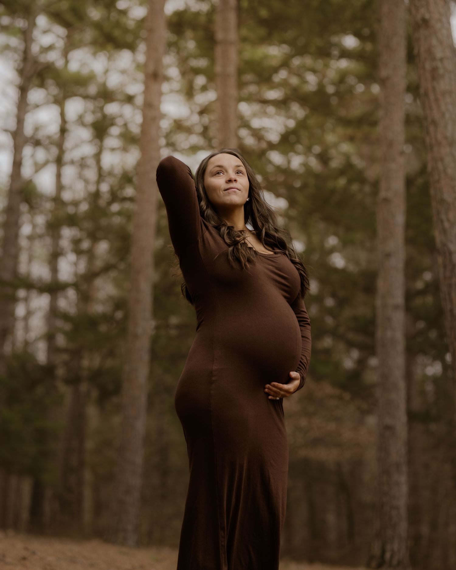 A series of artistic maternity portraits showing a woman in a brown dress posing expressively against a forest backdrop.