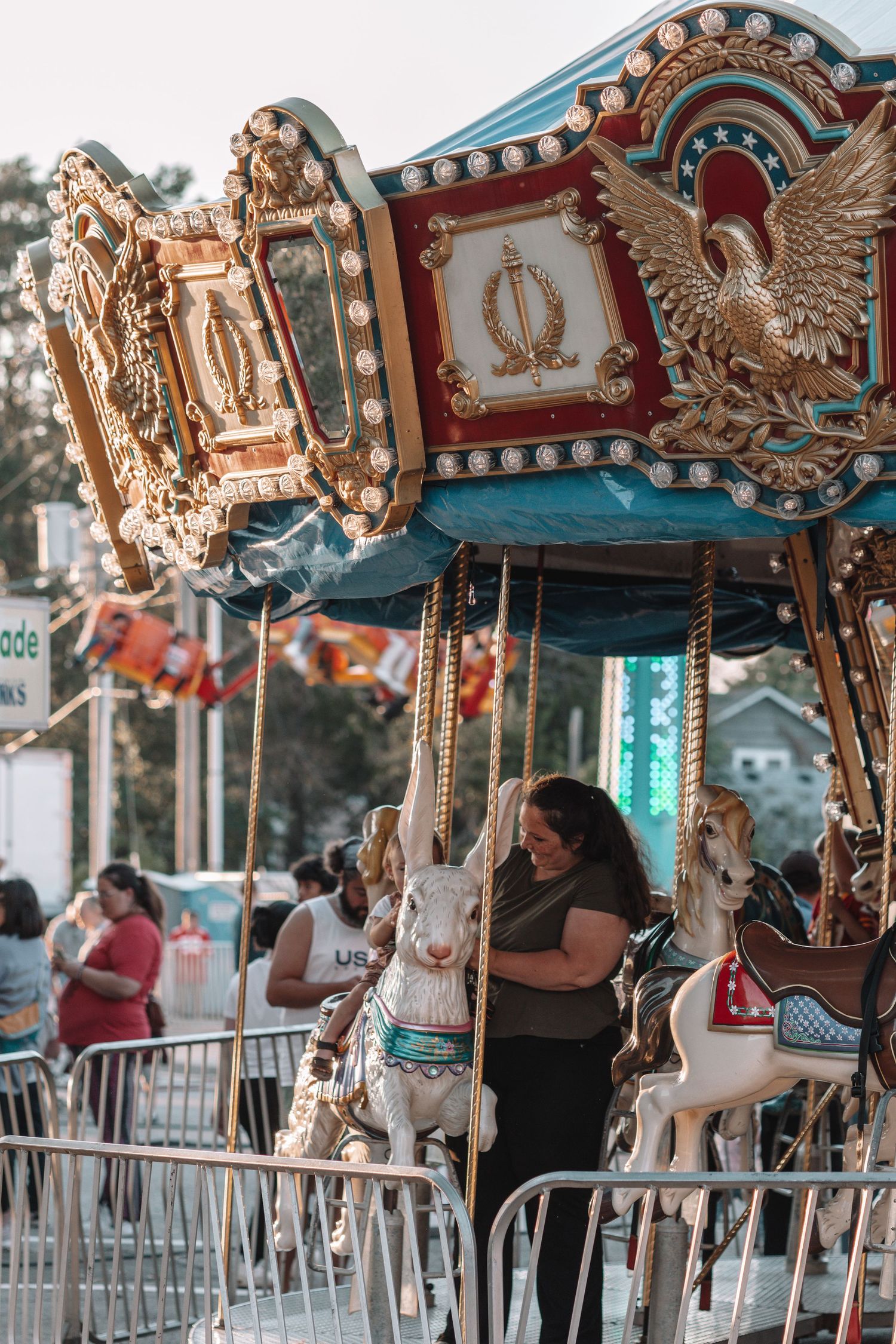 Vintage carousel with ornate gold and turquoise decorations featuring traditional painted horses at a carnival.