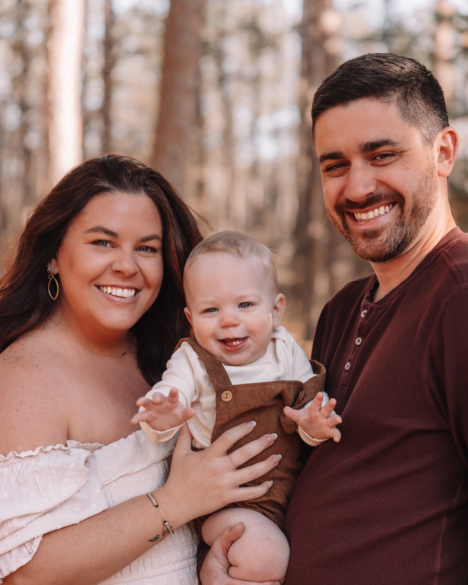 Family cuddles together during outdoor autumn photoshoot with warm lighting.