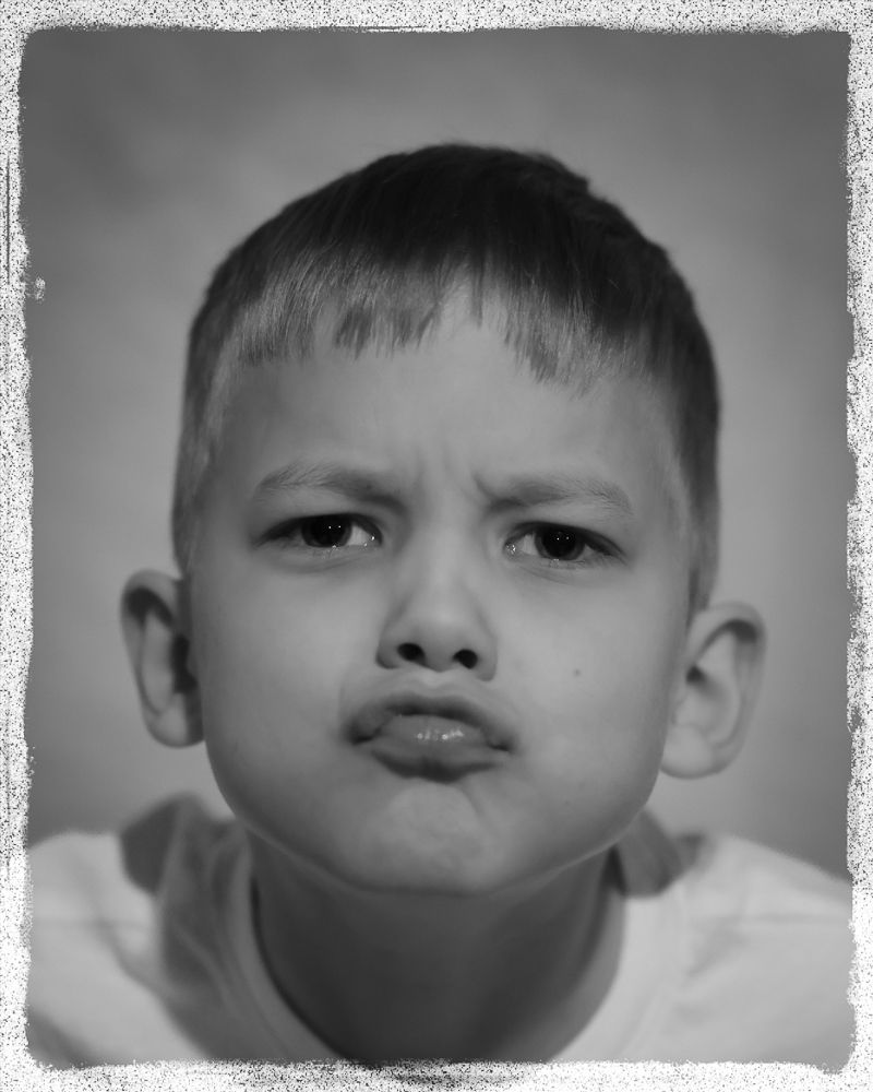 A black and white photo series showing close-up expressions of a young child's face with various moods and angles.