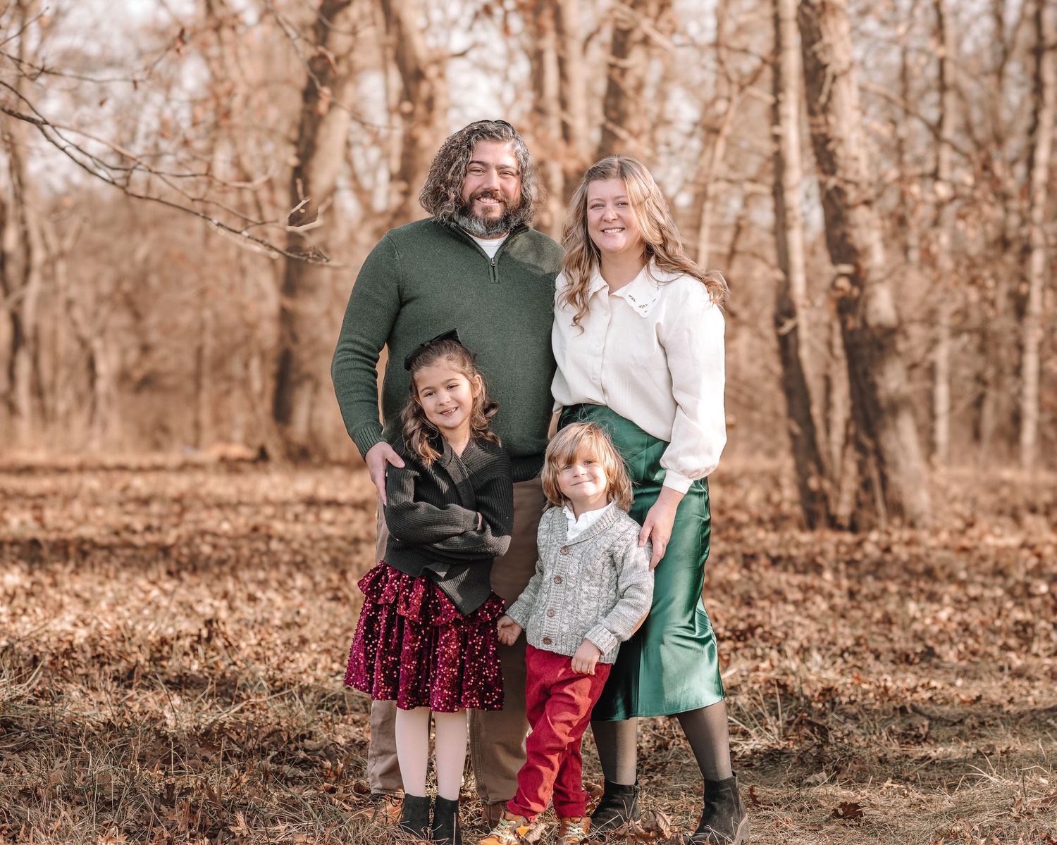 Family gathering outdoors in a wooded area during fall with muted brown tones in the background.