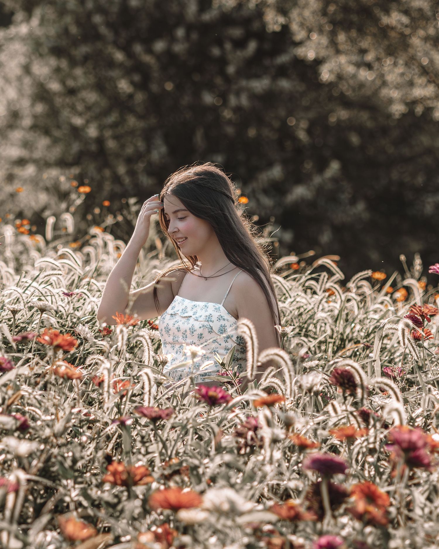 A person in a white top poses among blooming orange and red wildflowers during golden hour.