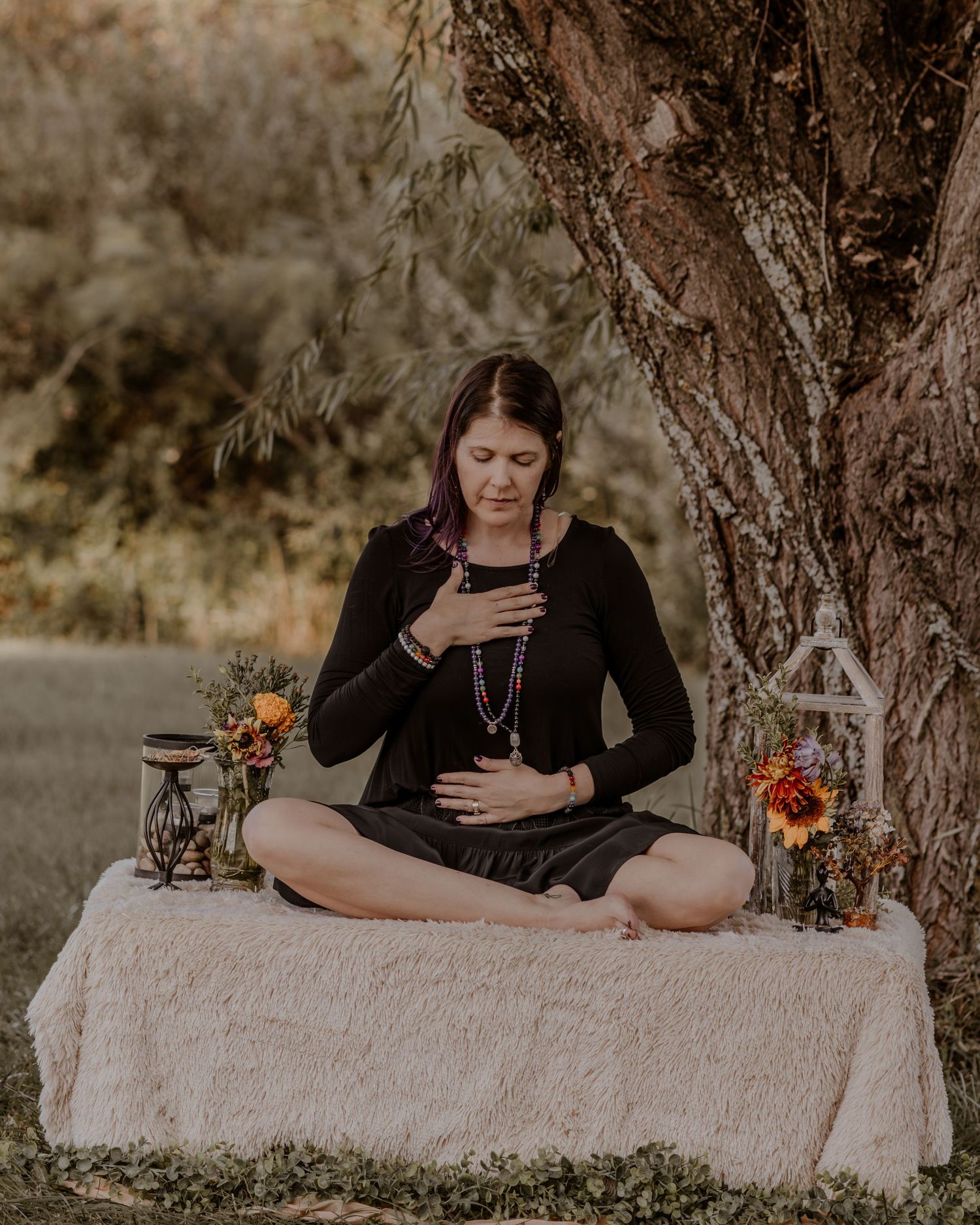 Outdoor maternity photoshoot featuring a cozy blanket setup with autumn floral arrangements and rustic decor.
