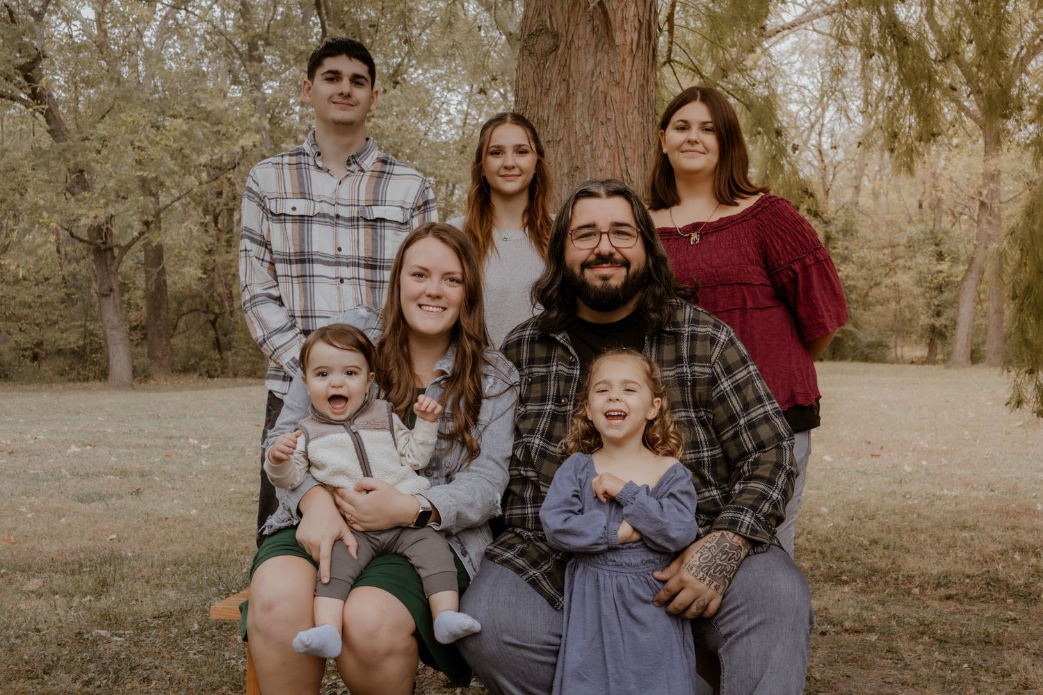 A series of outdoor family portraits taken in a park setting with warm autumn tones and natural lighting.