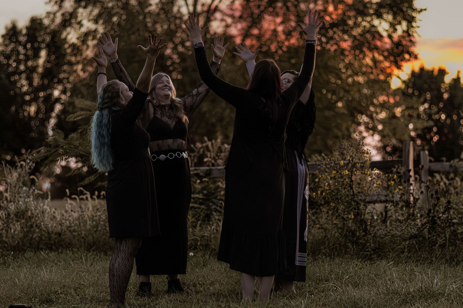 Group silhouettes celebrating outdoors during golden hour sunset.