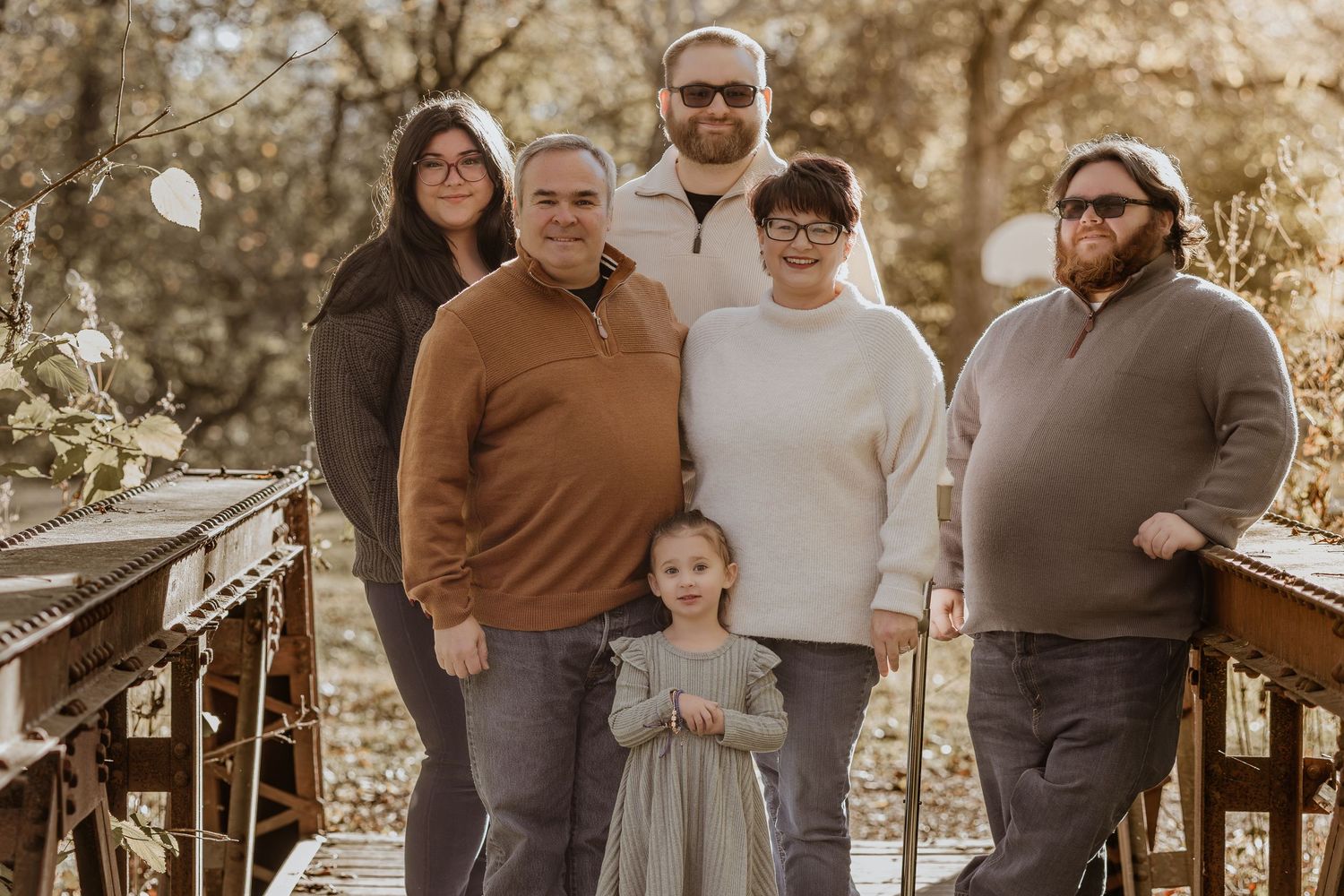 A family poses together outdoors during a golden hour photo session in autumn.