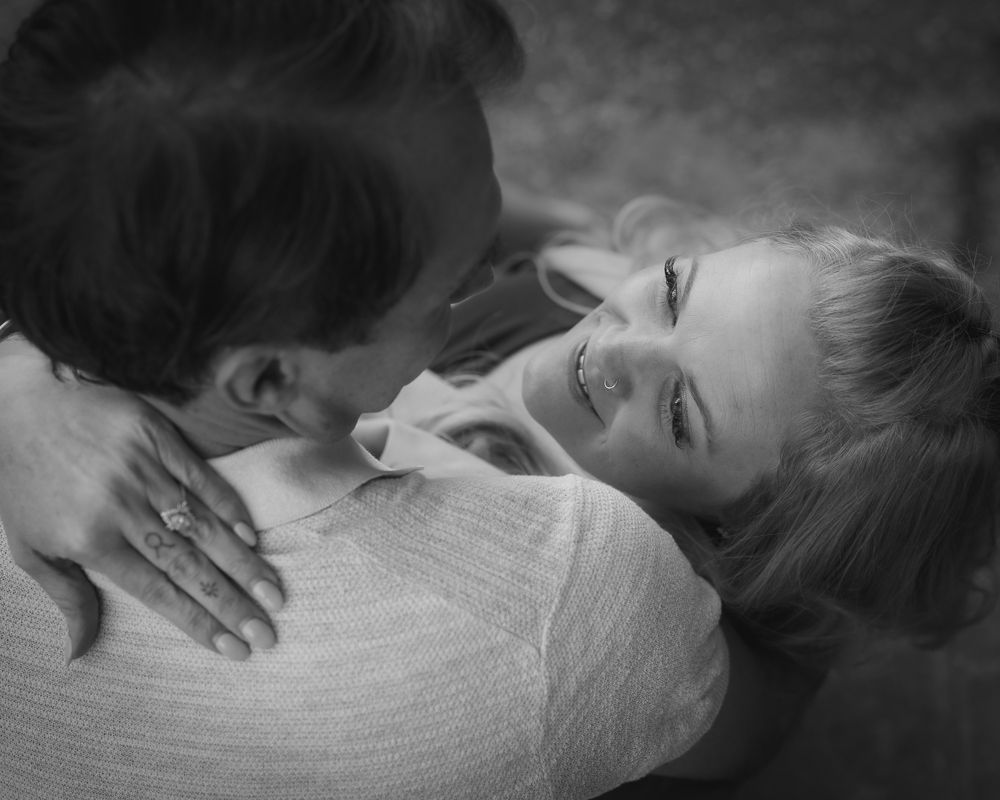 Black and white close-up portrait showing hands gently touching face in artistic composition.
