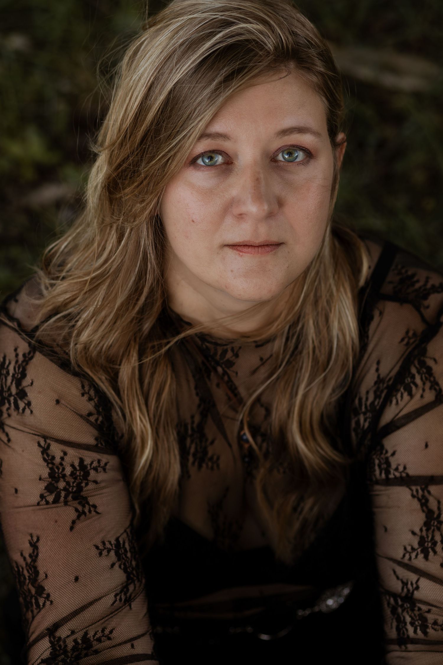 A dark and moody portrait featuring lace overlay and dramatic shadows.