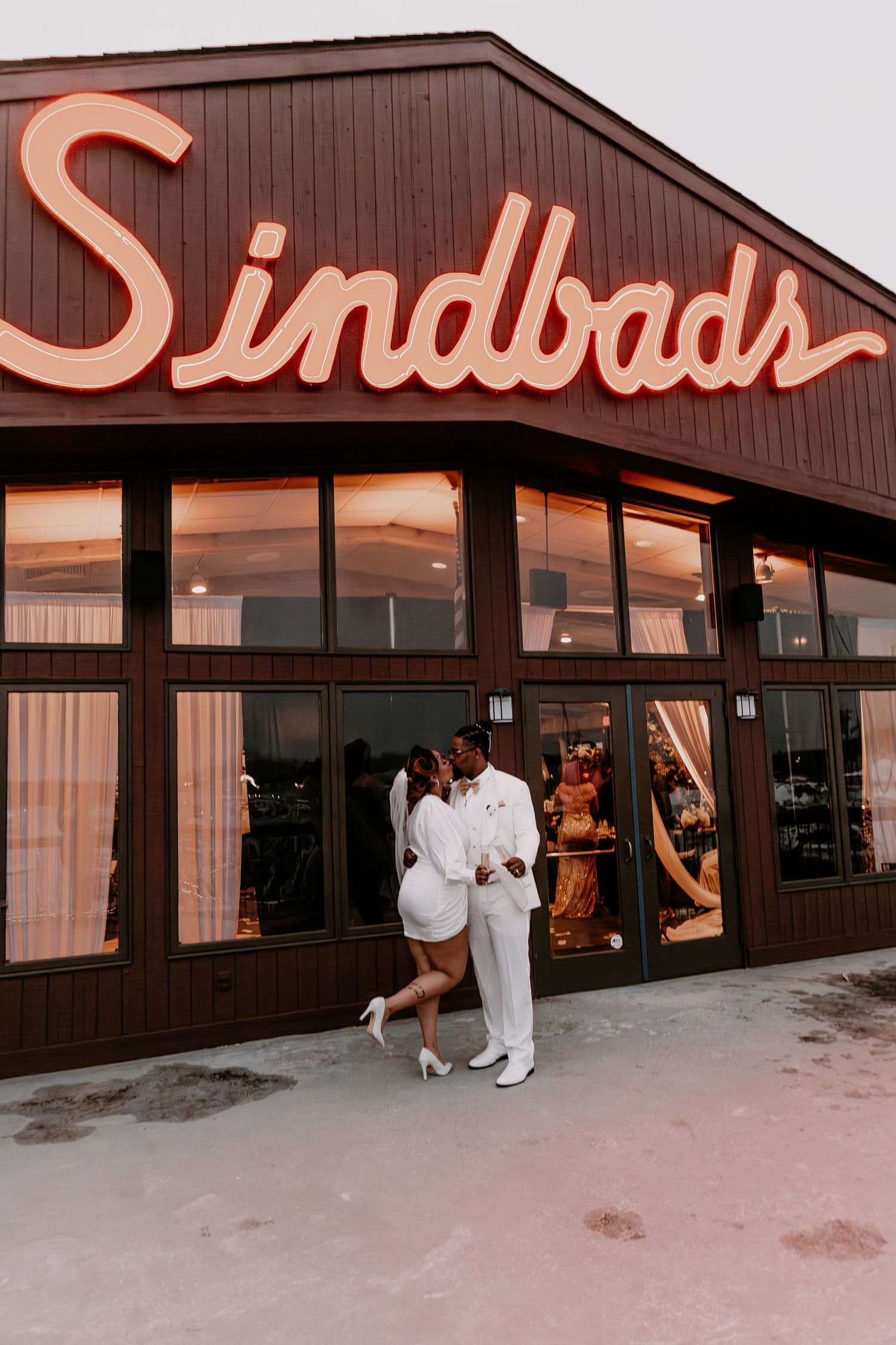 Couple embracing outside Sindbads restaurant during sunset.