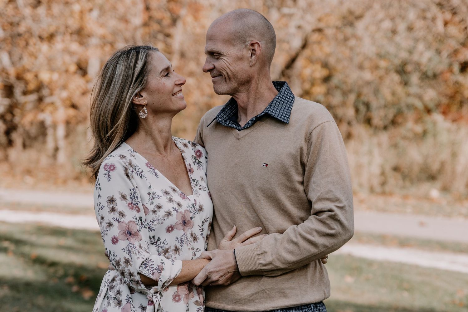 Couple sharing intimate moment outdoors with fall foliage scenery.