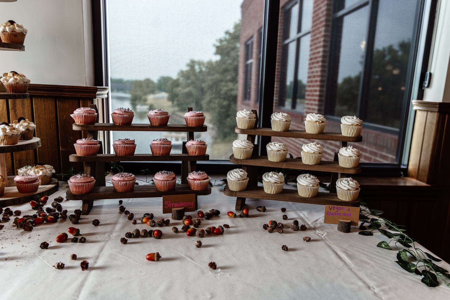 Display of elegant wedding cupcakes arranged on tiered stands with floral decorations.