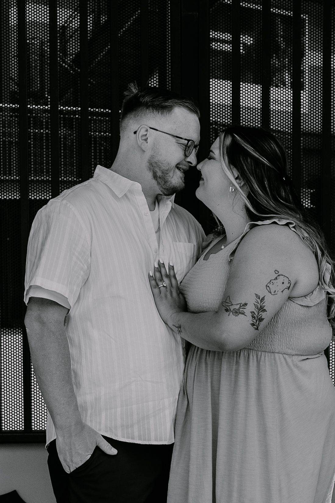 A romantic black and white portrait of a couple sharing an intimate moment, with the woman wearing a flowy dress.