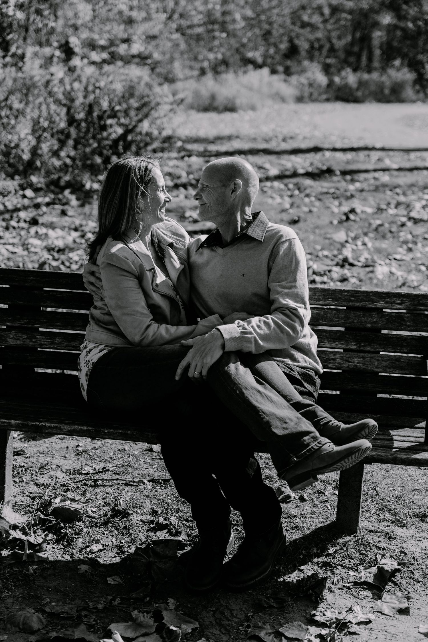 Couple relaxing together on park bench in black and white photography.