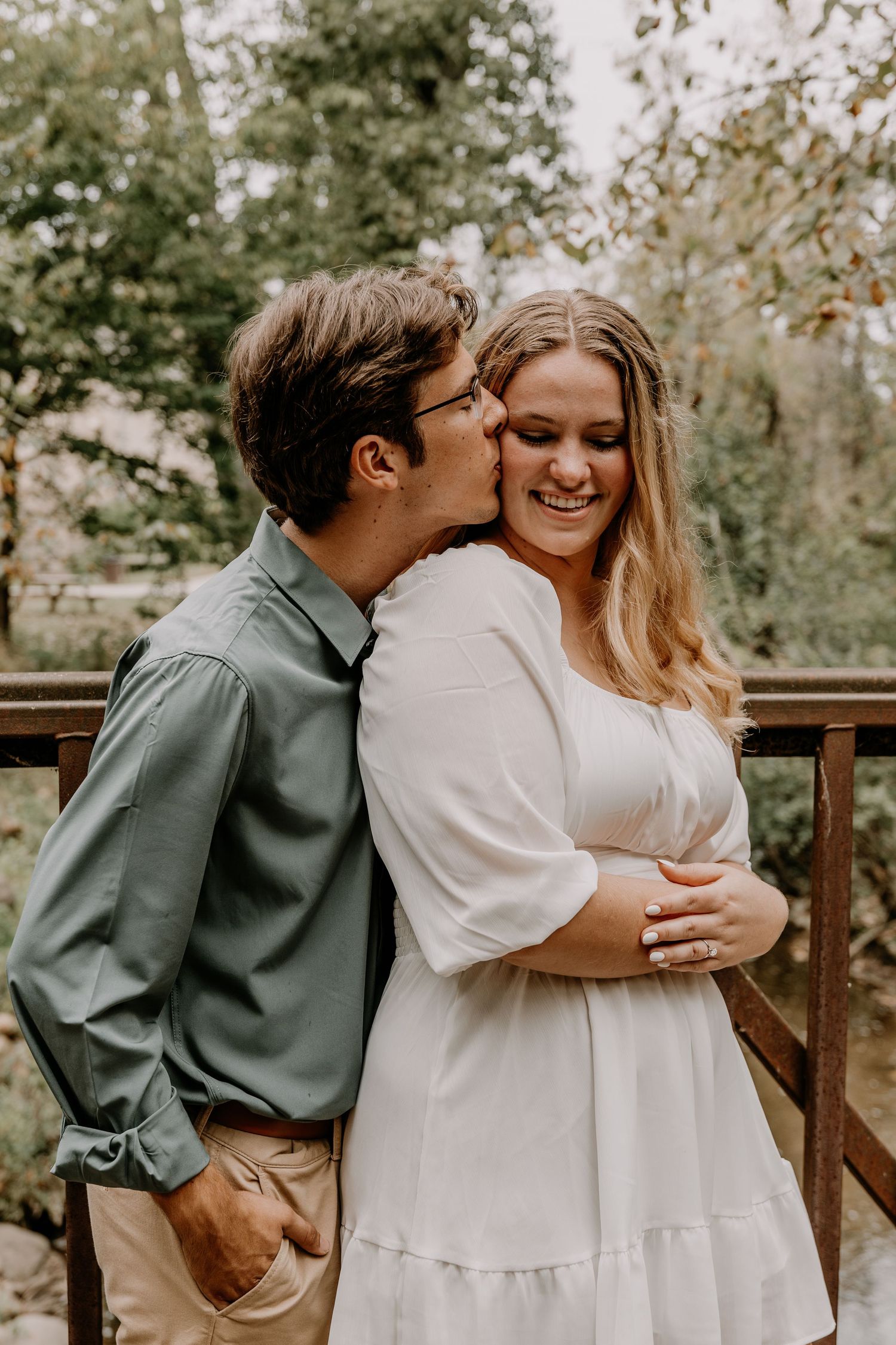 Tender moment between couple during forest engagement photoshoot.
