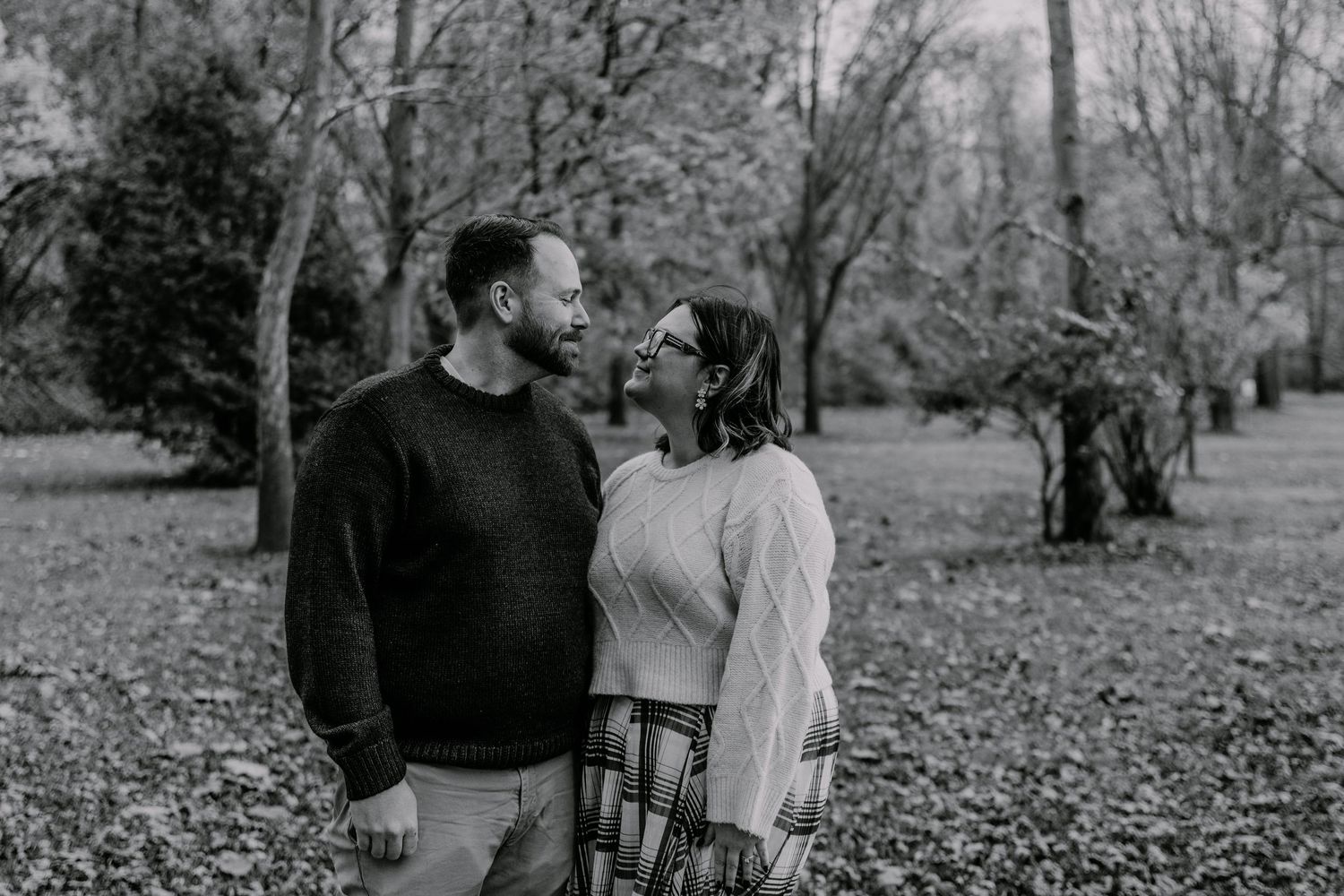 A black and white photo series captures a romantic couple walking through a park during autumn.