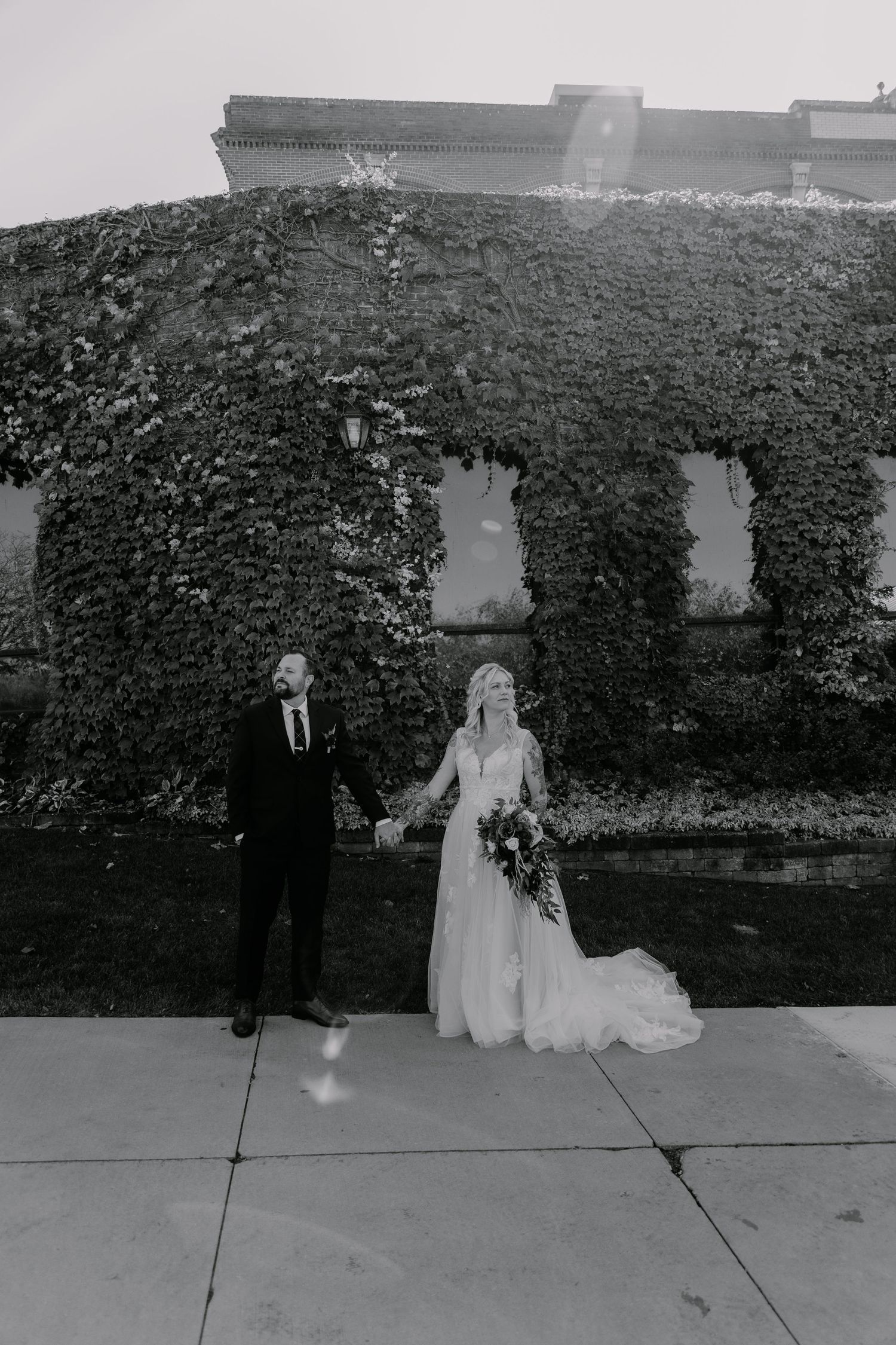 A sequence of black and white photos showing a couple in wedding attire posing against an ivy-covered wall.