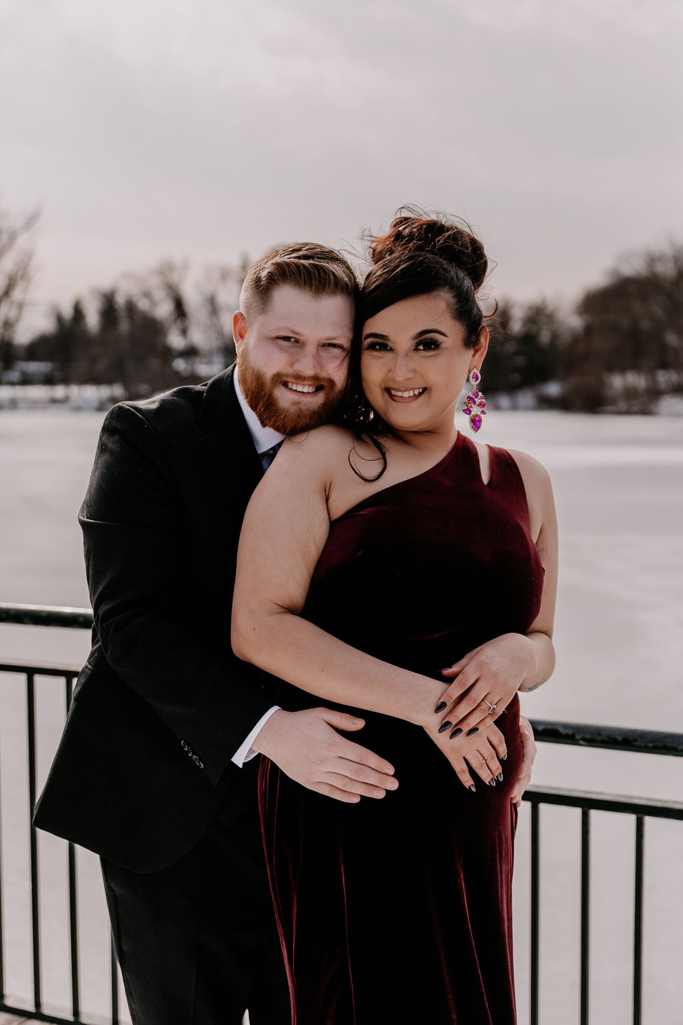 A couple in formal attire posing on a snowy balcony.