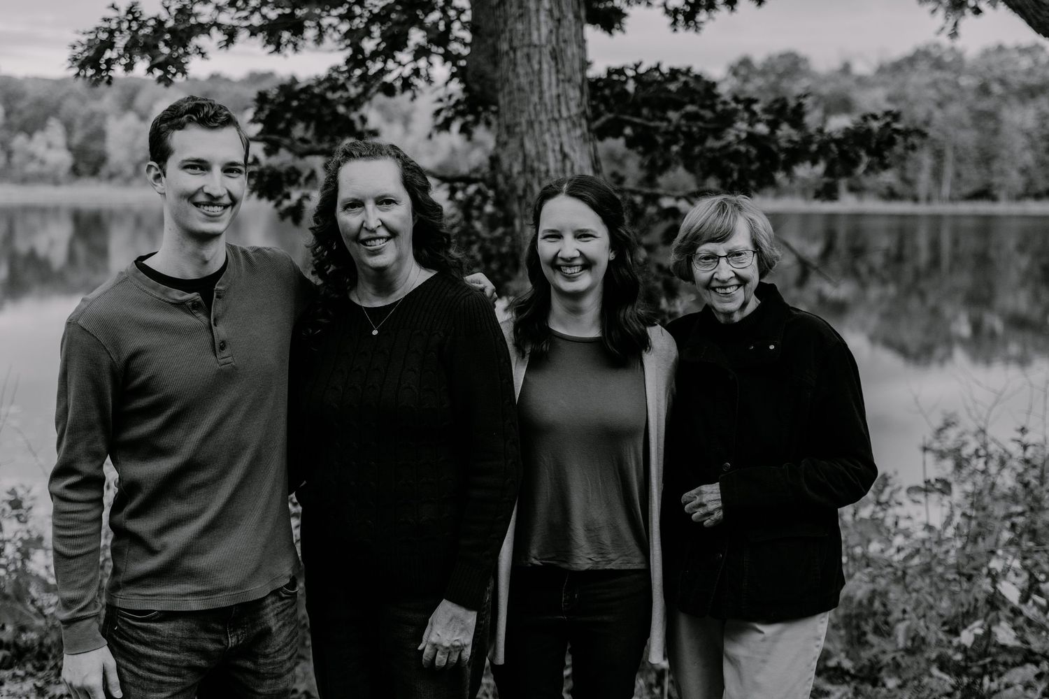 Group portrait outdoors under tree branches in casual attire.