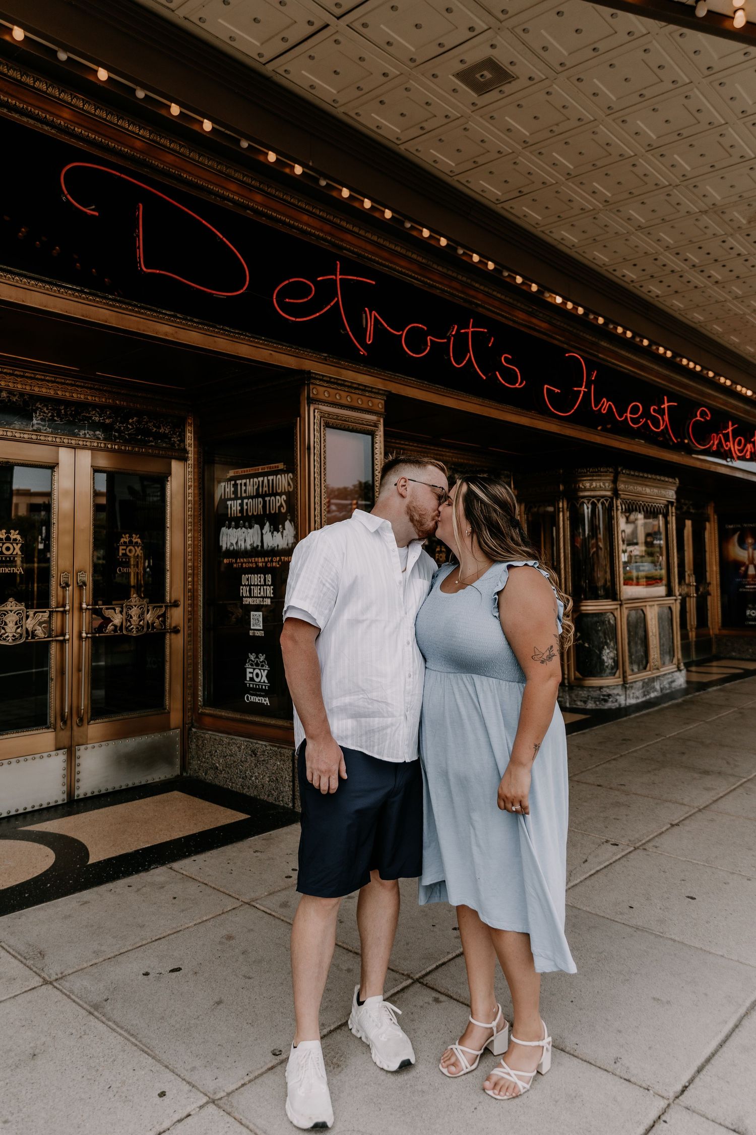 A romantic moment captured outside Detroit's Finest building with string lights overhead and vintage storefront details.