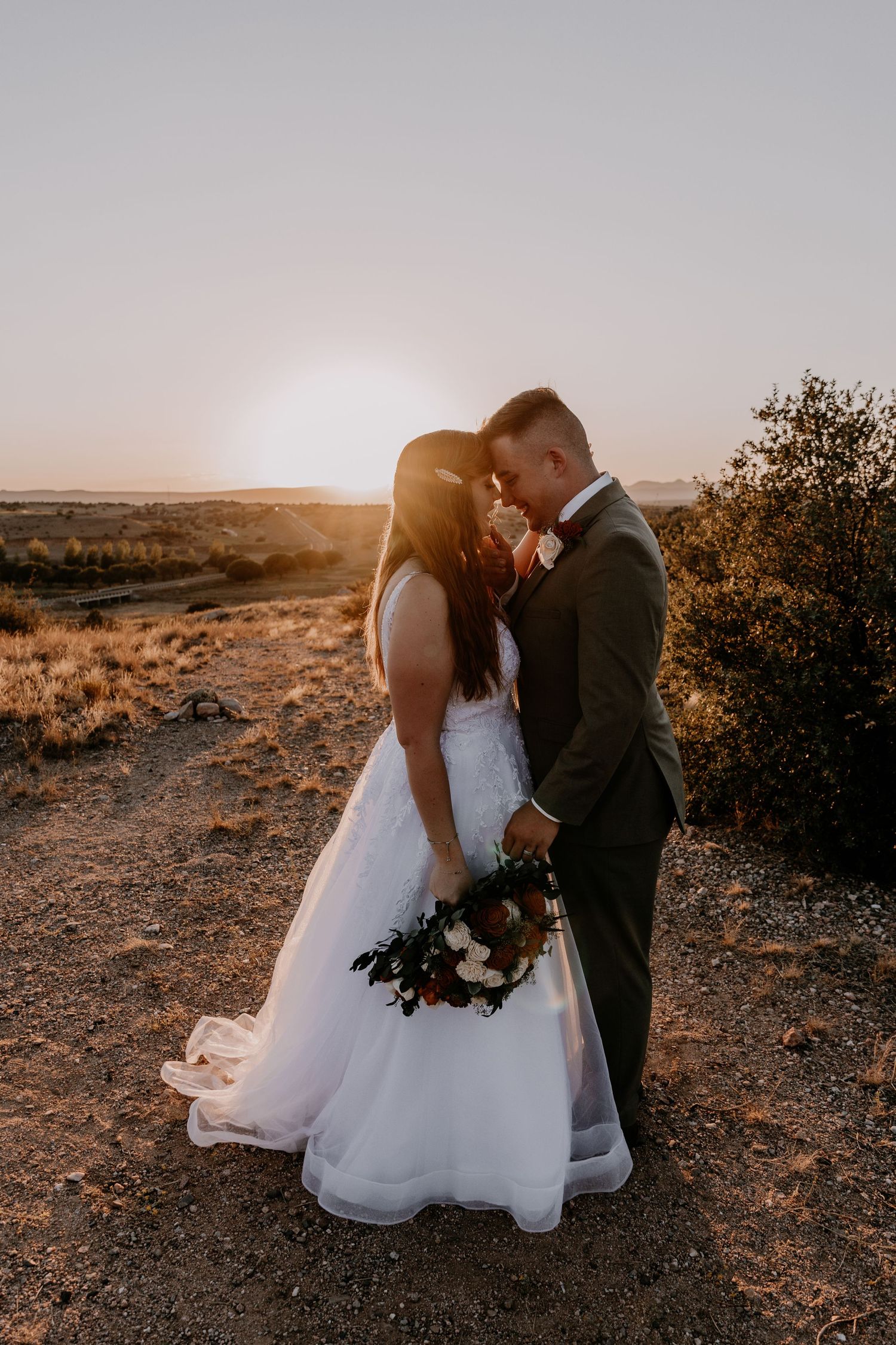 Close embrace between newlyweds during intimate desert sunset wedding photo session.