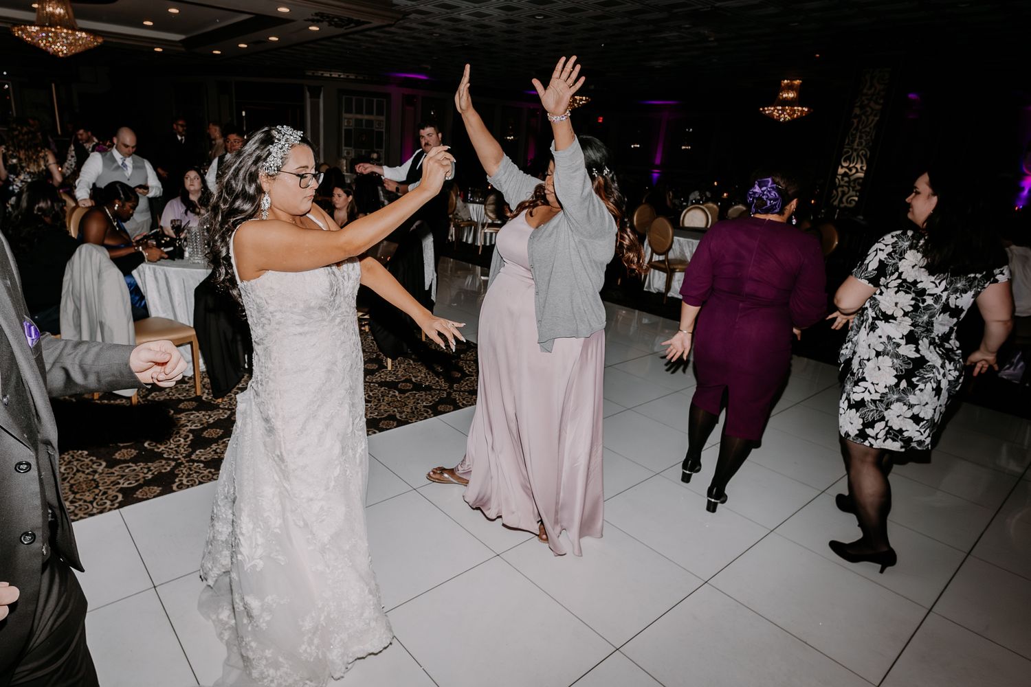 Wedding reception dancing with bride and guests celebrating on a white dance floor.