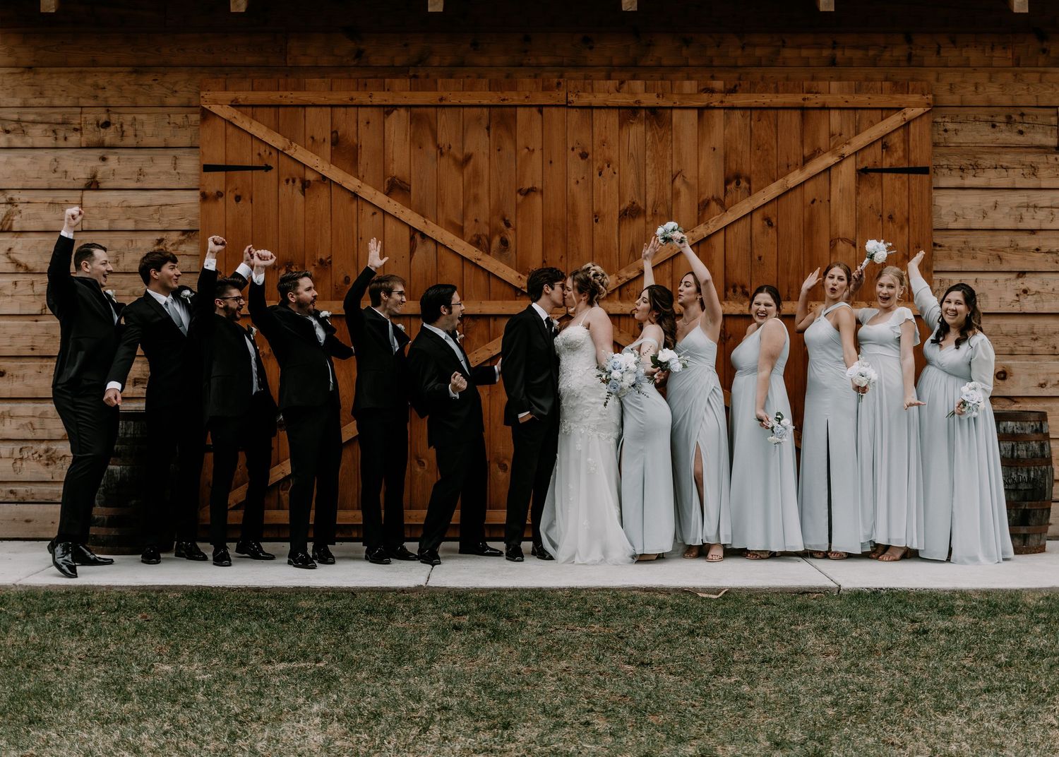 Wedding party group photo with bridesmaids in light gowns and groomsmen in dark suits.