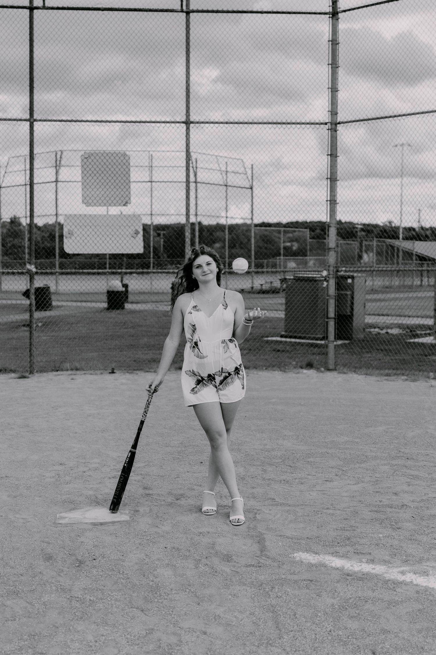 Black and white photo showing athletic poses on a sports field with fencing in the background.