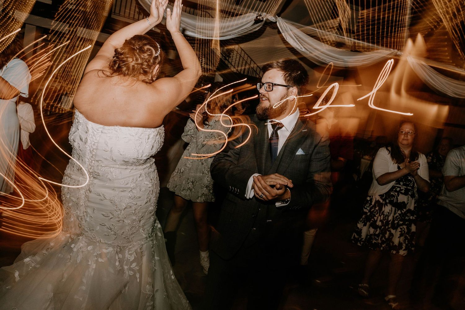 Wedding couple dancing under dramatic lighting at their reception with motion blur effects.