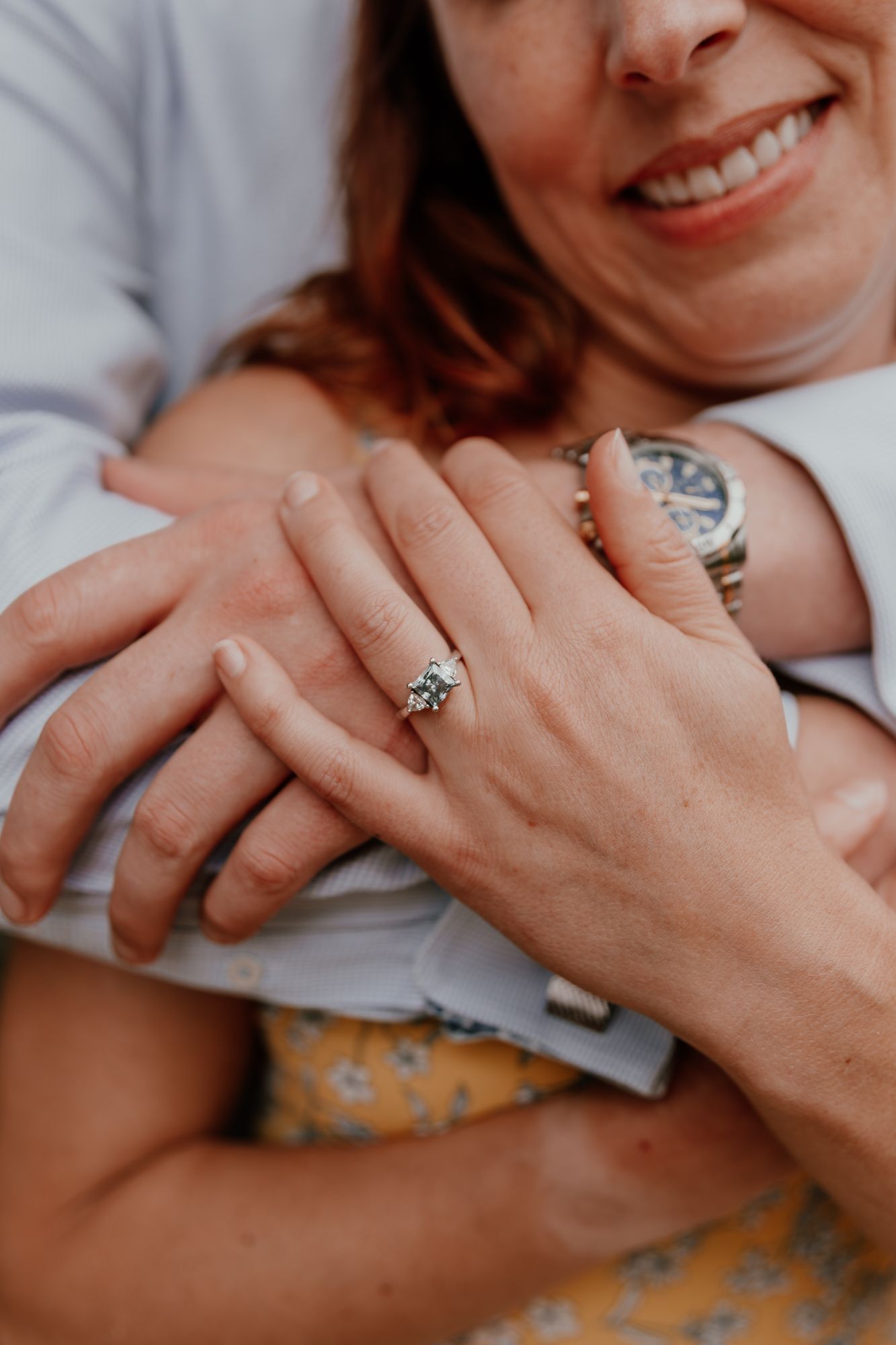 Close up of hands showing off an engagement ring with a beautiful diamond solitaire.