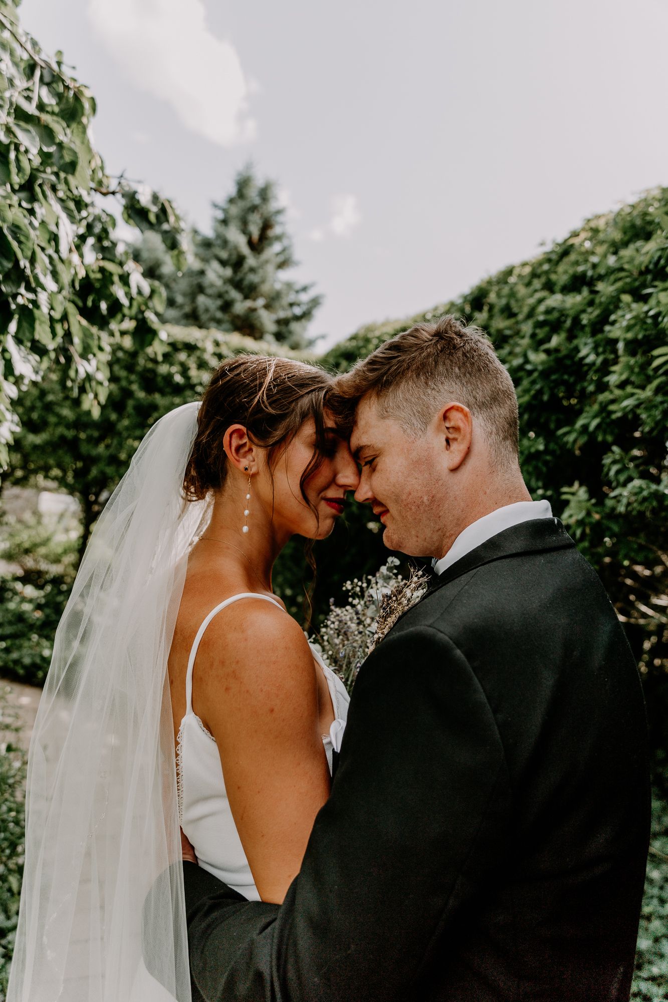 Romantic portrait of couple touching foreheads in garden setting.