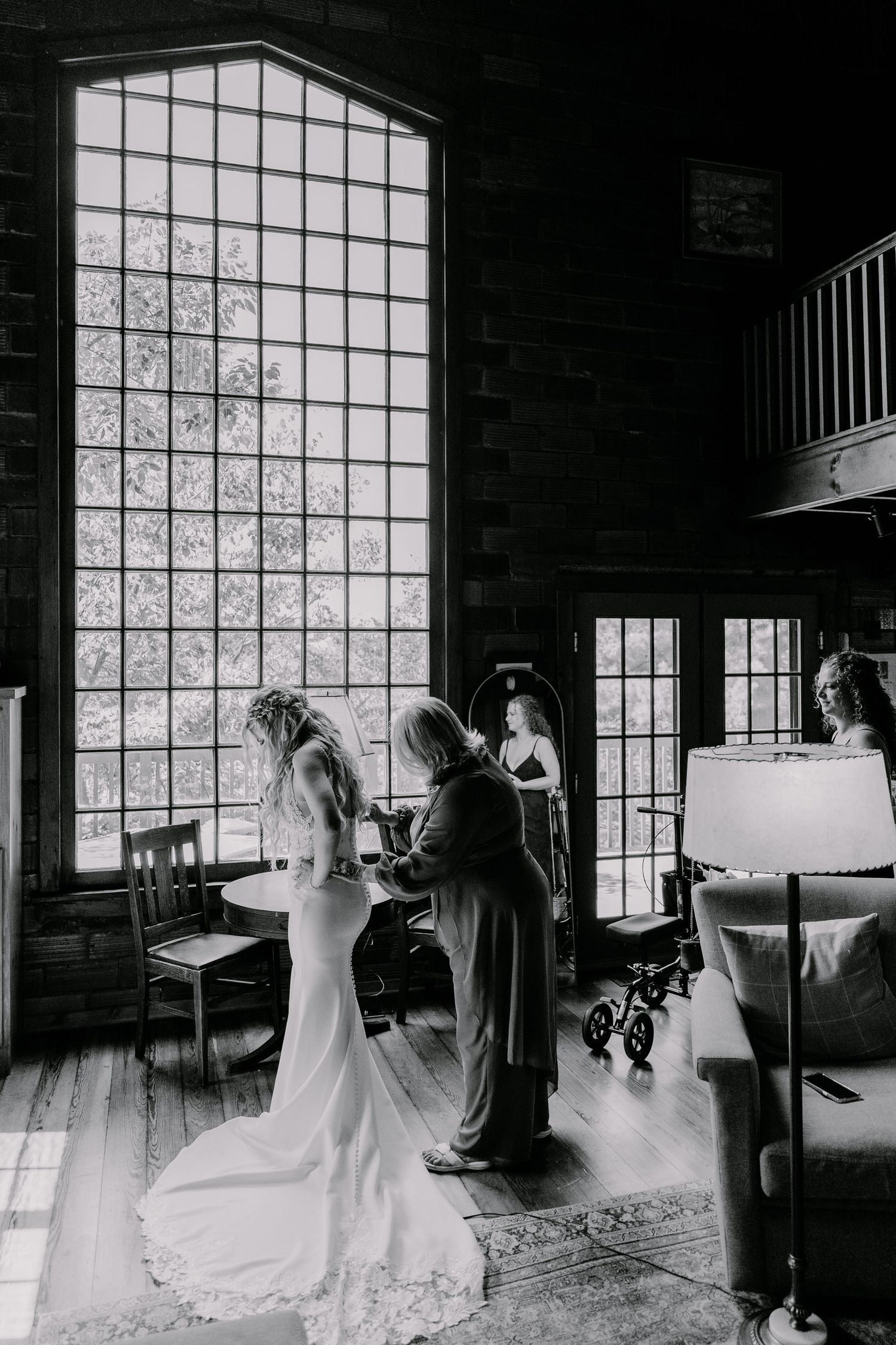 Wedding ceremony in a rustic venue with dramatic lighting through a large gridded window.